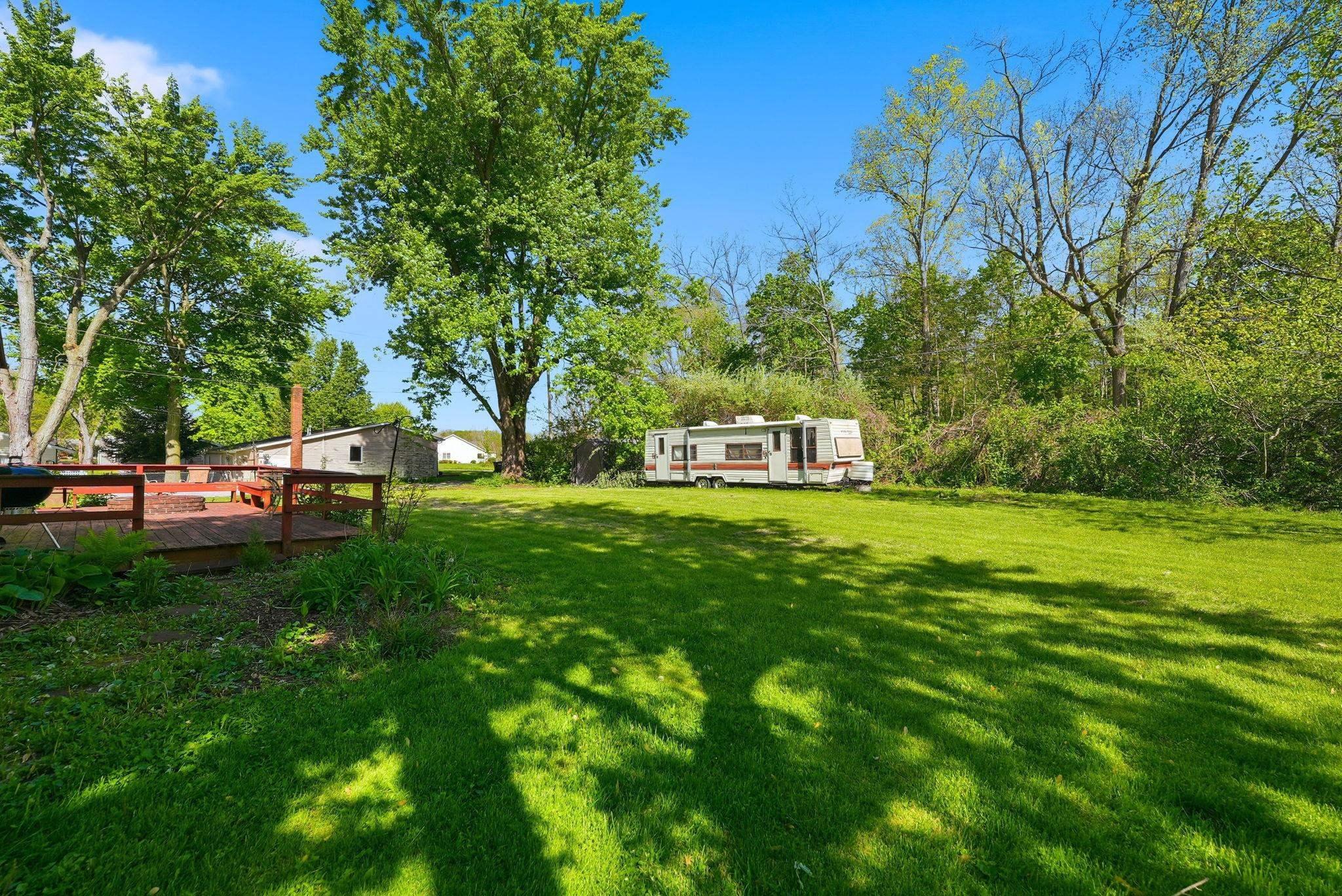 Image 3: Expansive green lawn with mature trees, featuring a wood-finish deck with railings, Yard Image 3: Expansive green lawn with mature trees, featuring a wood-finish deck with railings, Yard