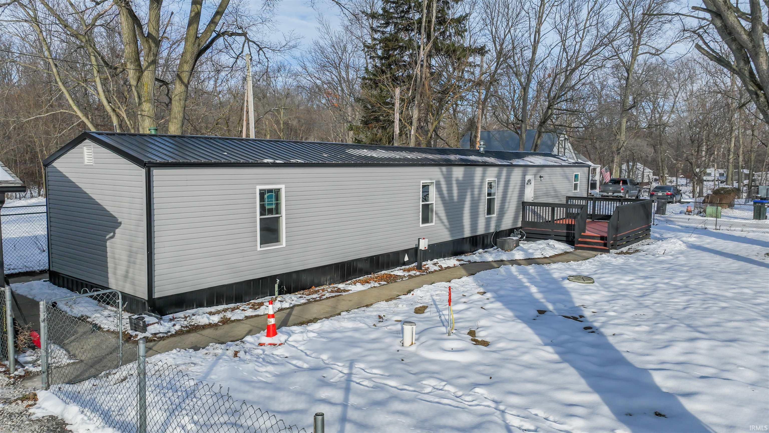 Image 0: Snow covered property featuring a wooden deck and a metal roof, Side Of Structure