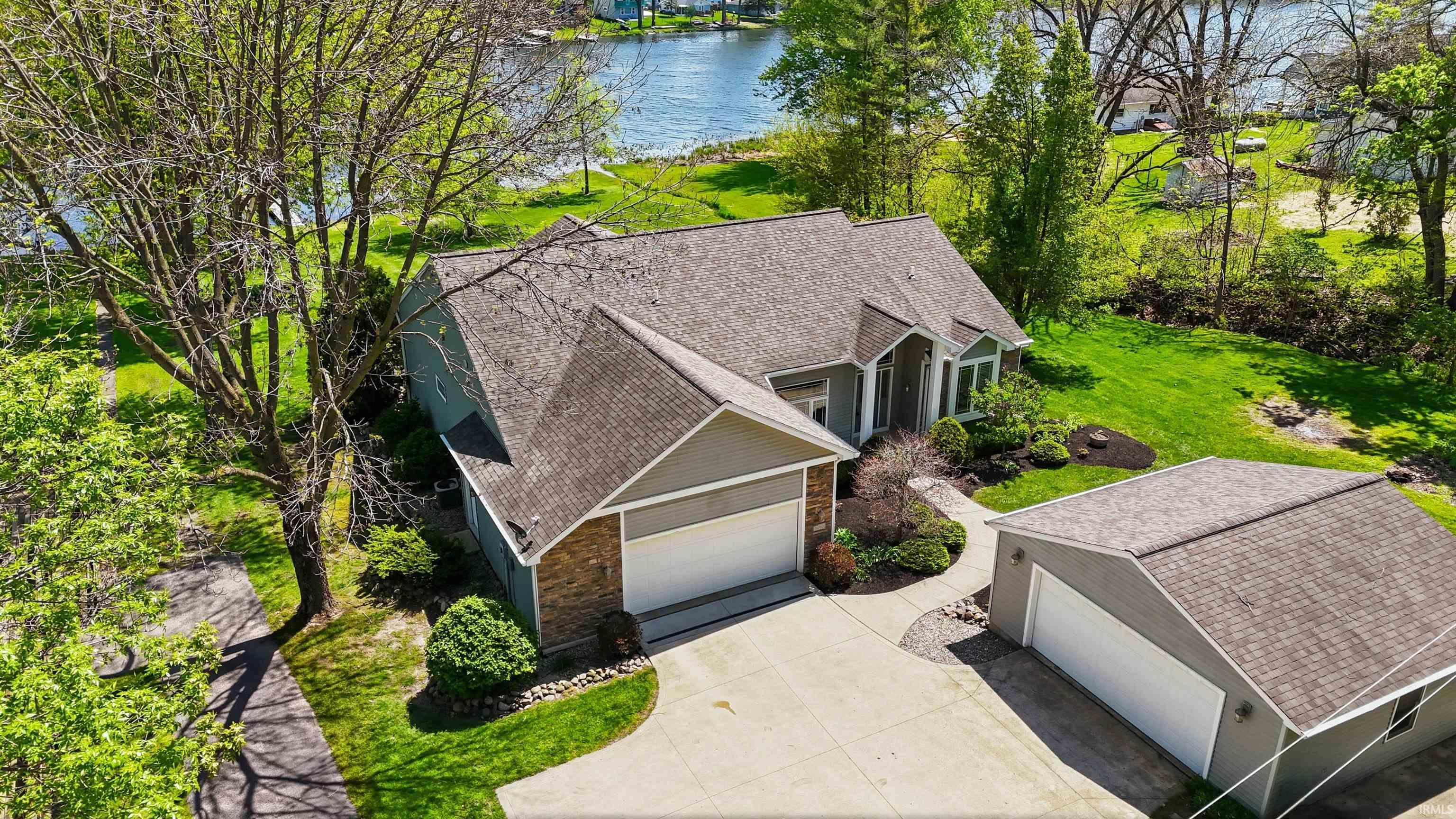 Image 2: Waterfront property featuring a detached garage, expansive lawn, and mature trees, Aerial View Image 2: Waterfront property featuring a detached garage, expansive lawn, and mature trees, Aerial View