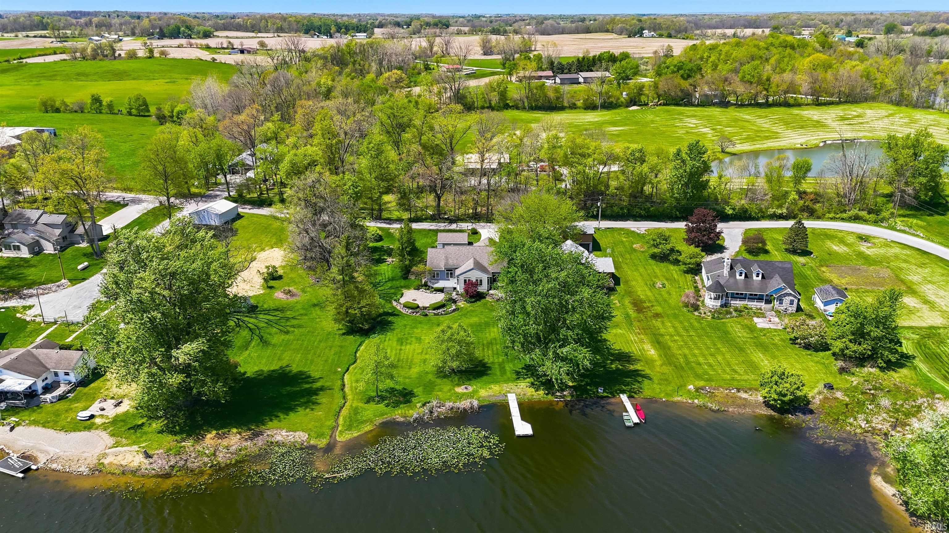 Image 3: Waterfront property featuring a private dock, expansive green lawn, mature trees, and a gravel shoreline, Aerial View Image 3: Waterfront property featuring a private dock, expansive green lawn, mature trees, and a gravel shoreline, Aerial View