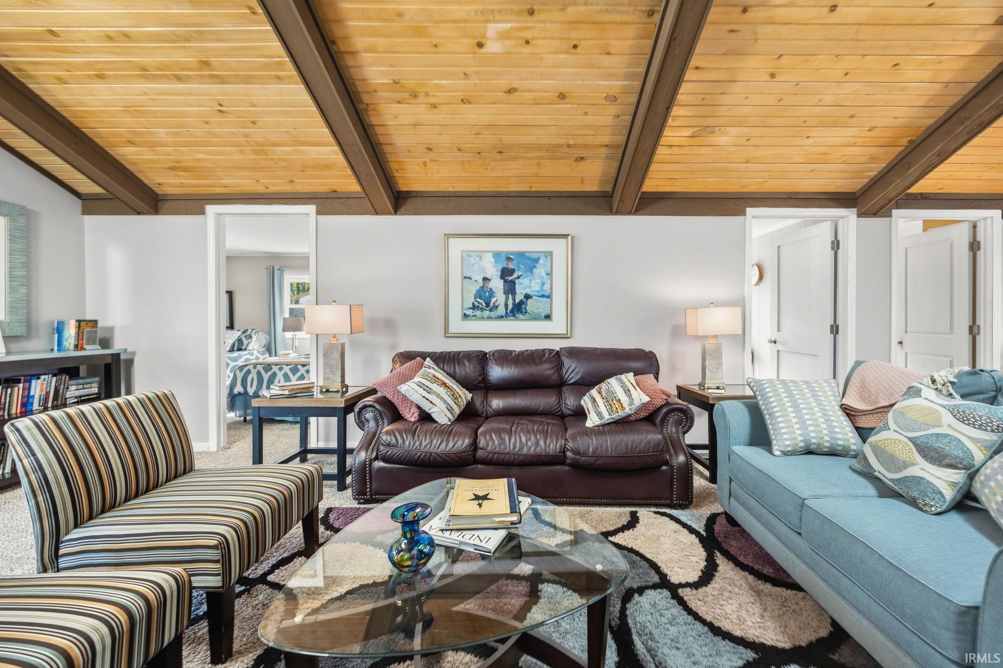 Image 3: Exposed wood-plank ceiling with dark beams over a carpeted living space, Living Room
