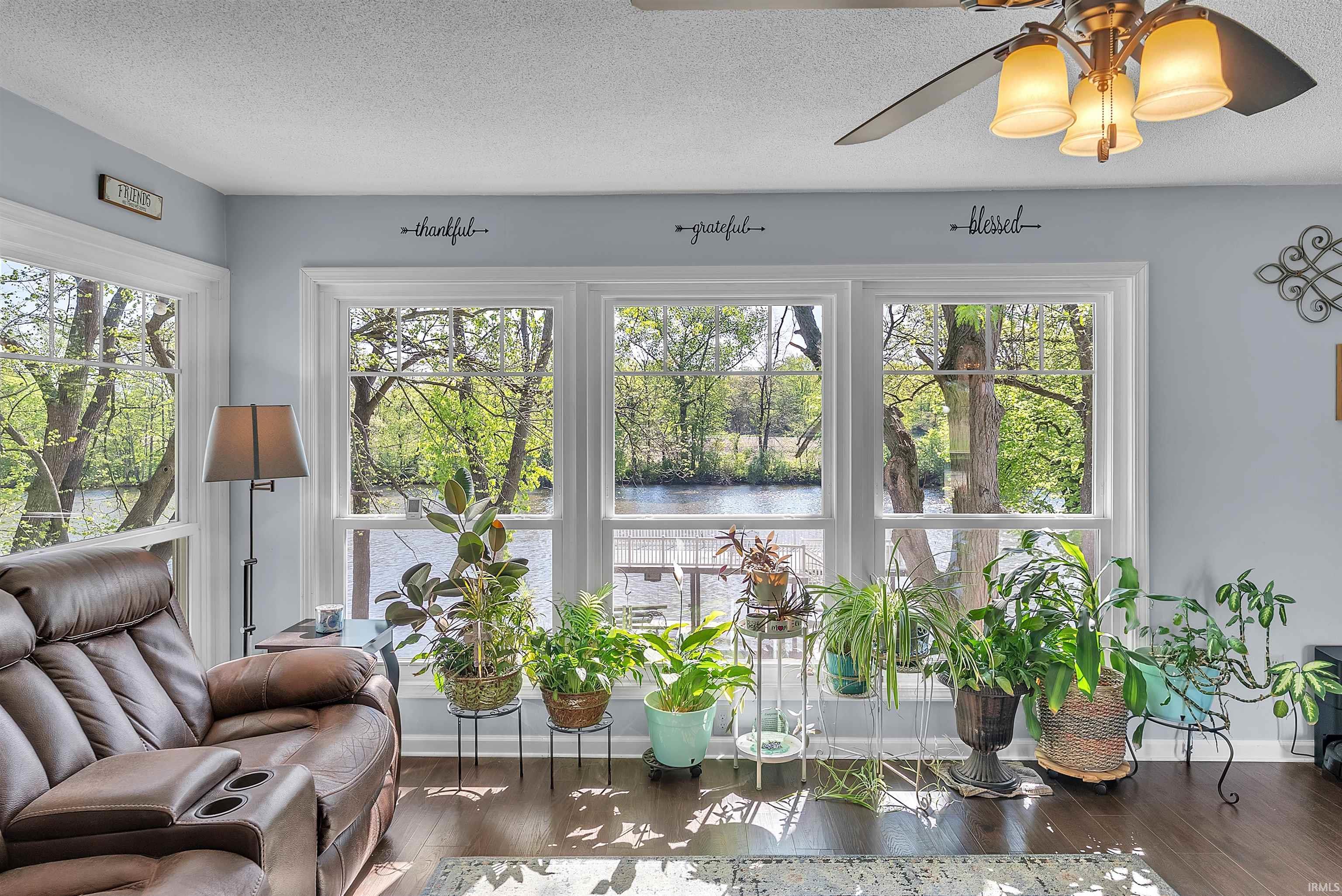 Image 1: Bright interior room with wood-finish flooring and a multi-light ceiling fan, Sun Room