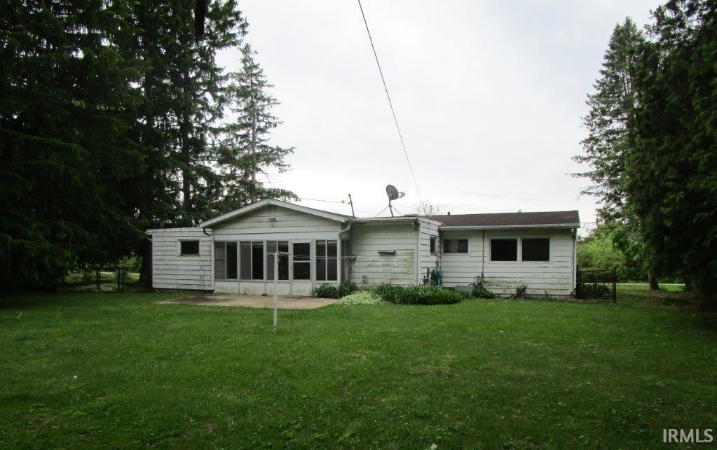 Image 2: Spacious backyard featuring a large sunroom with multiple windows, a concrete patio, and mature perimeter trees, Back Of Structure Image 2: Spacious backyard featuring a large sunroom with multiple windows, a concrete patio, and mature perimeter trees, Back Of Structure