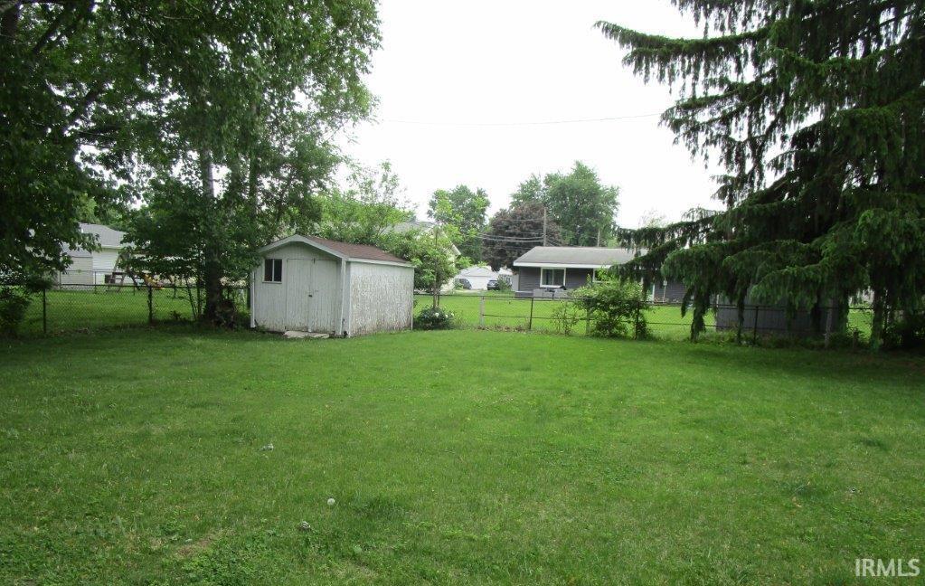 Image 3: Spacious backyard featuring a storage shed with a shingled roof and single window, mature trees providing natural shading, and a wire fence enclosing the perimeter, Yard Image 3: Spacious backyard featuring a storage shed with a shingled roof and single window, mature trees providing natural shading, and a wire fence enclosing the perimeter, Yard