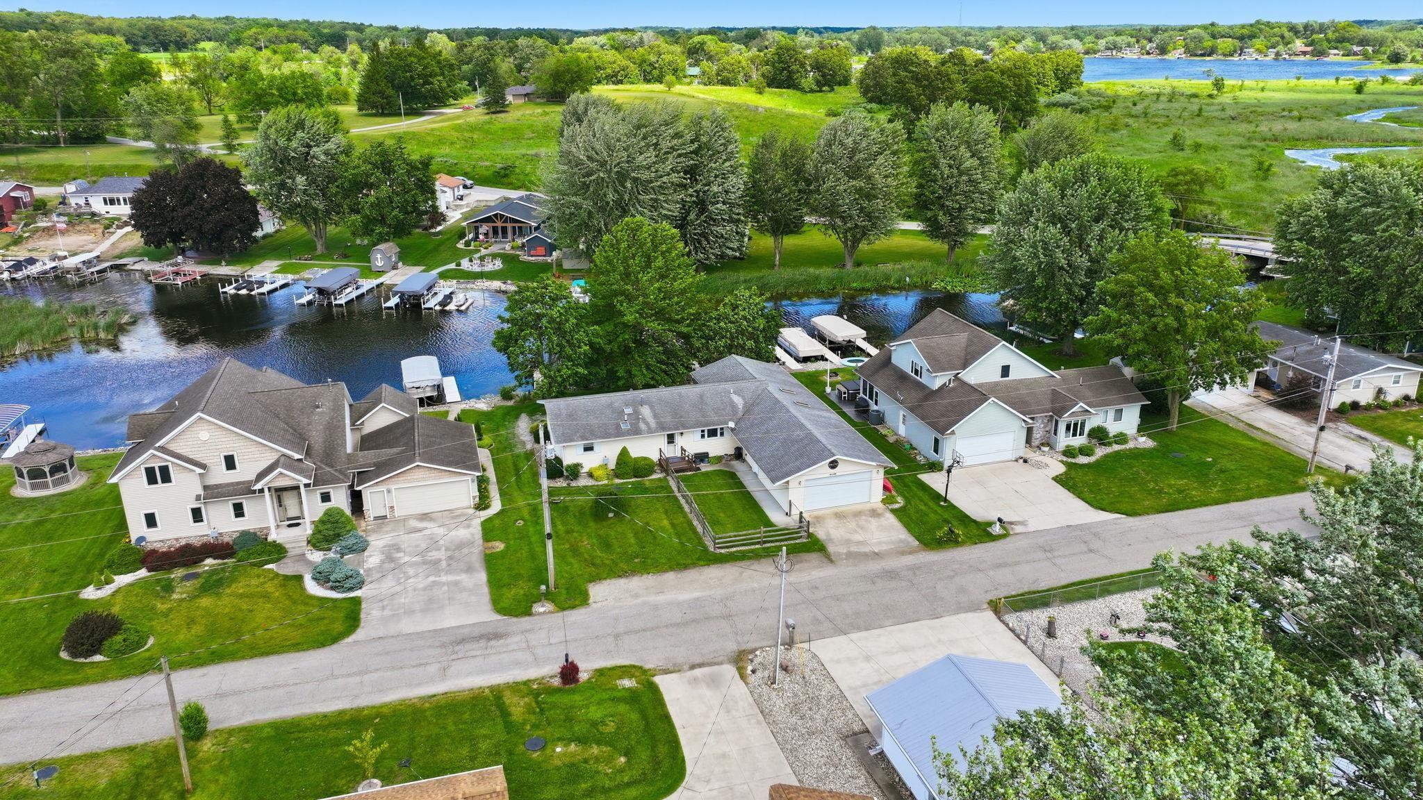 Image 3: Waterfront property featuring a private boat dock, mature landscaping, and an attached two-car garage, Aerial View