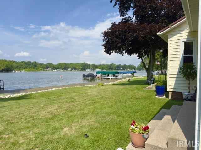Image 3: Expansive waterfront lawn featuring a private dock with boat lift, mature shade trees, and steps leading to the property entrance, Yard Image 3: Expansive waterfront lawn featuring a private dock with boat lift, mature shade trees, and steps leading to the property entrance, Yard