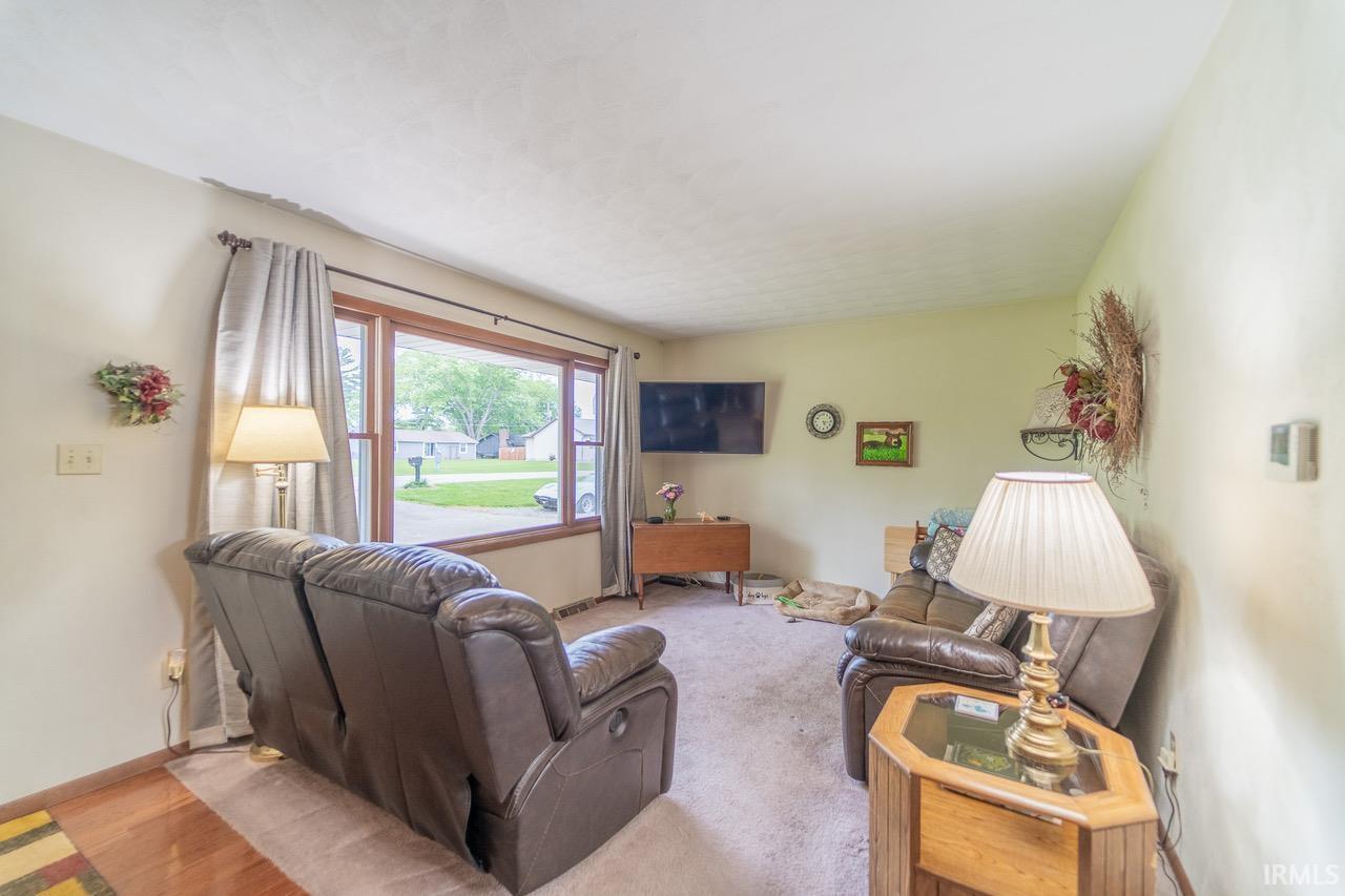 Image 1: Spacious living area featuring a large picture window, light-toned walls, and mixed flooring with wood-finish sections, Living Room Image 1: Spacious living area featuring a large picture window, light-toned walls, and mixed flooring with wood-finish sections, Living Room