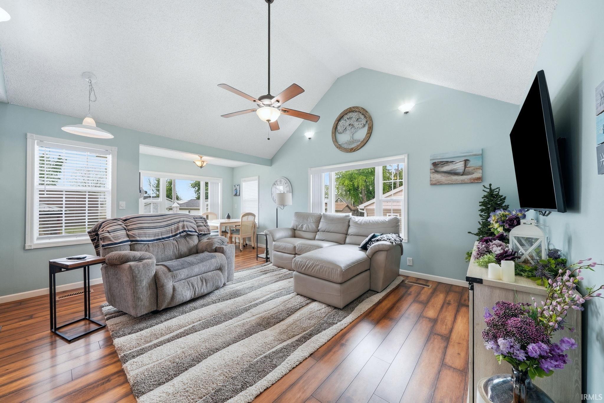 Image 1: Spacious living area featuring vaulted ceilings, wood-finish flooring, and ample natural light from multiple windows, Living Room Image 1: Spacious living area featuring vaulted ceilings, wood-finish flooring, and ample natural light from multiple windows, Living Room