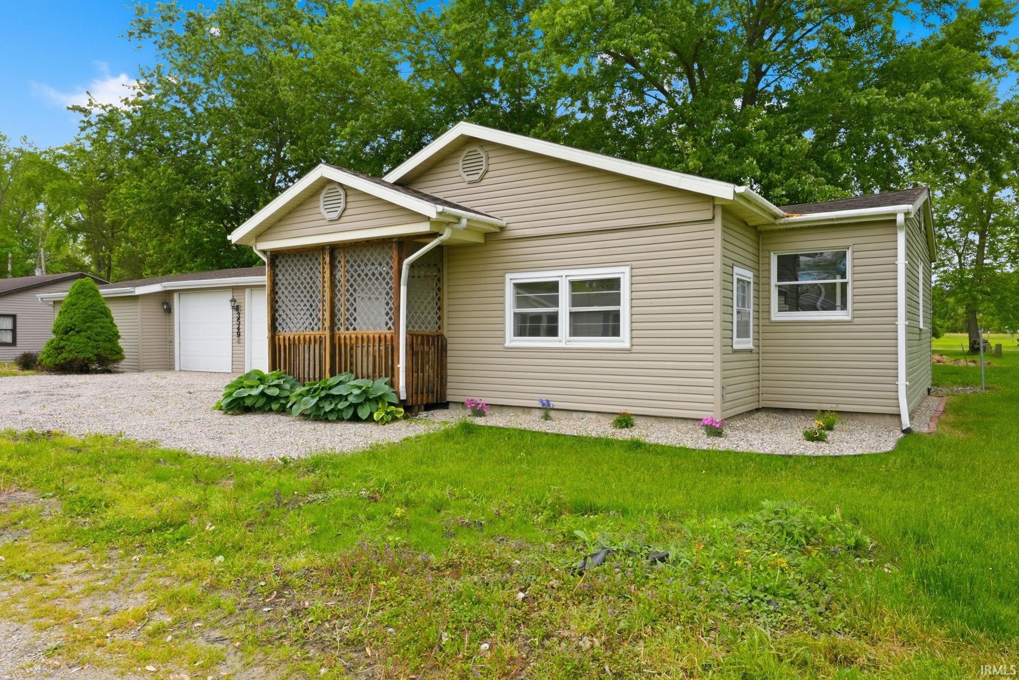 Image 0: Single-story residence featuring light tan vinyl siding and white trim accents, Front Of Structure