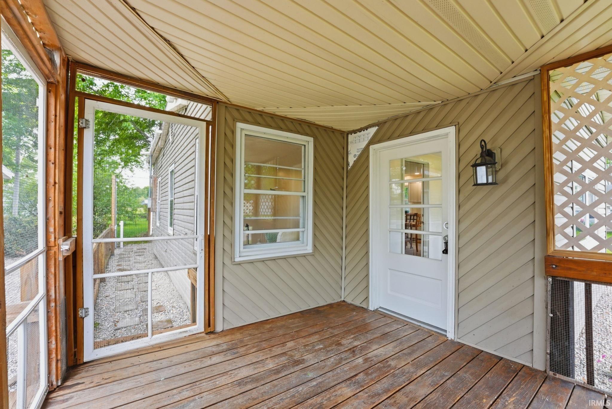 Image 3: Screened porch with wood-finish flooring, diagonal siding, and a white paneled door with glass inserts, Sun Room