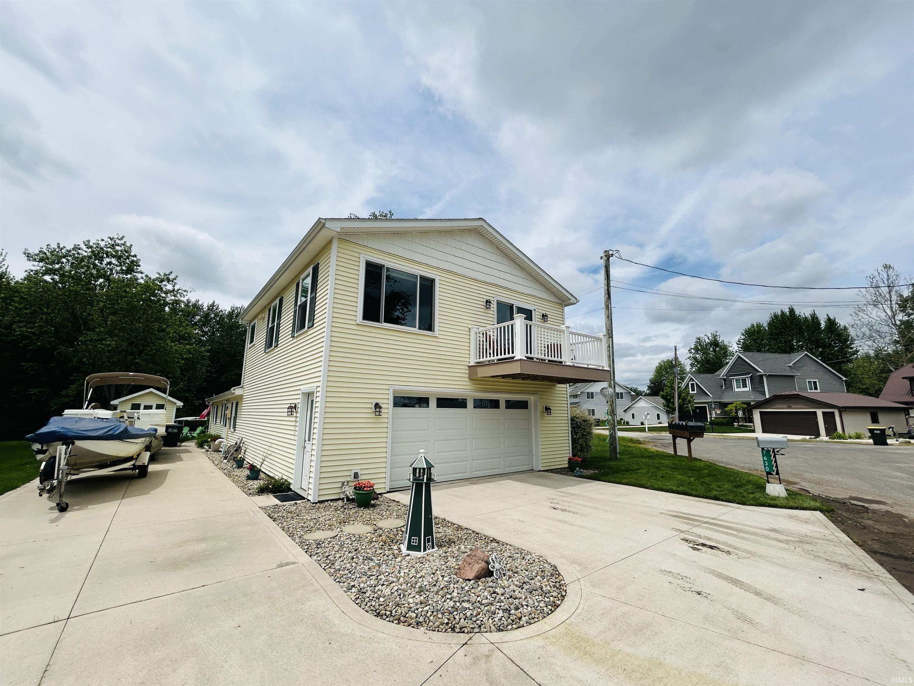 Image 2: Light yellow siding exterior with white trim and a second-story balcony, Side Of Structure Image 2: Light yellow siding exterior with white trim and a second-story balcony, Side Of Structure