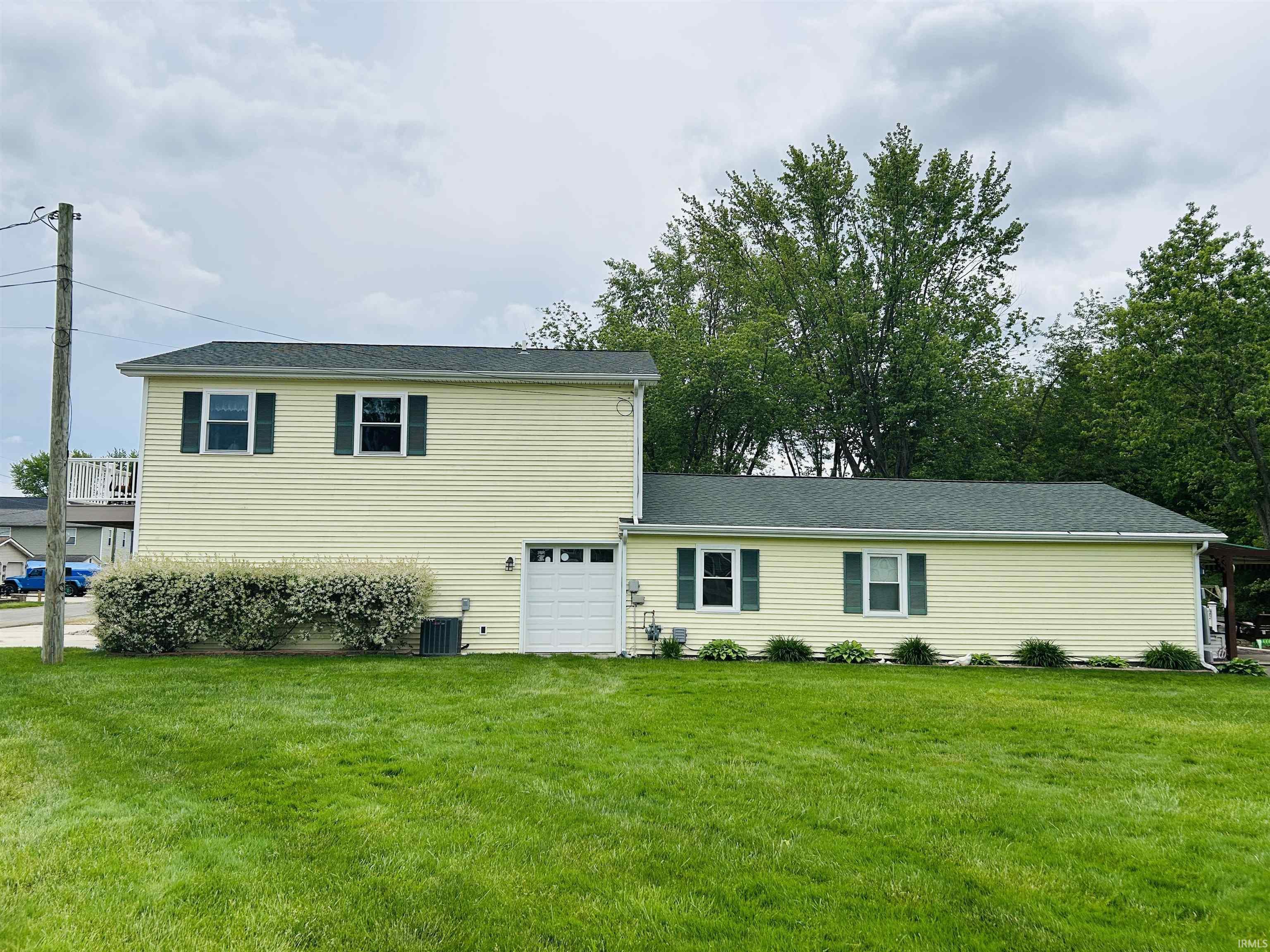Image 3: Two-story residence featuring light yellow siding and a dark green roof, Front Of Structure Image 3: Two-story residence featuring light yellow siding and a dark green roof, Front Of Structure