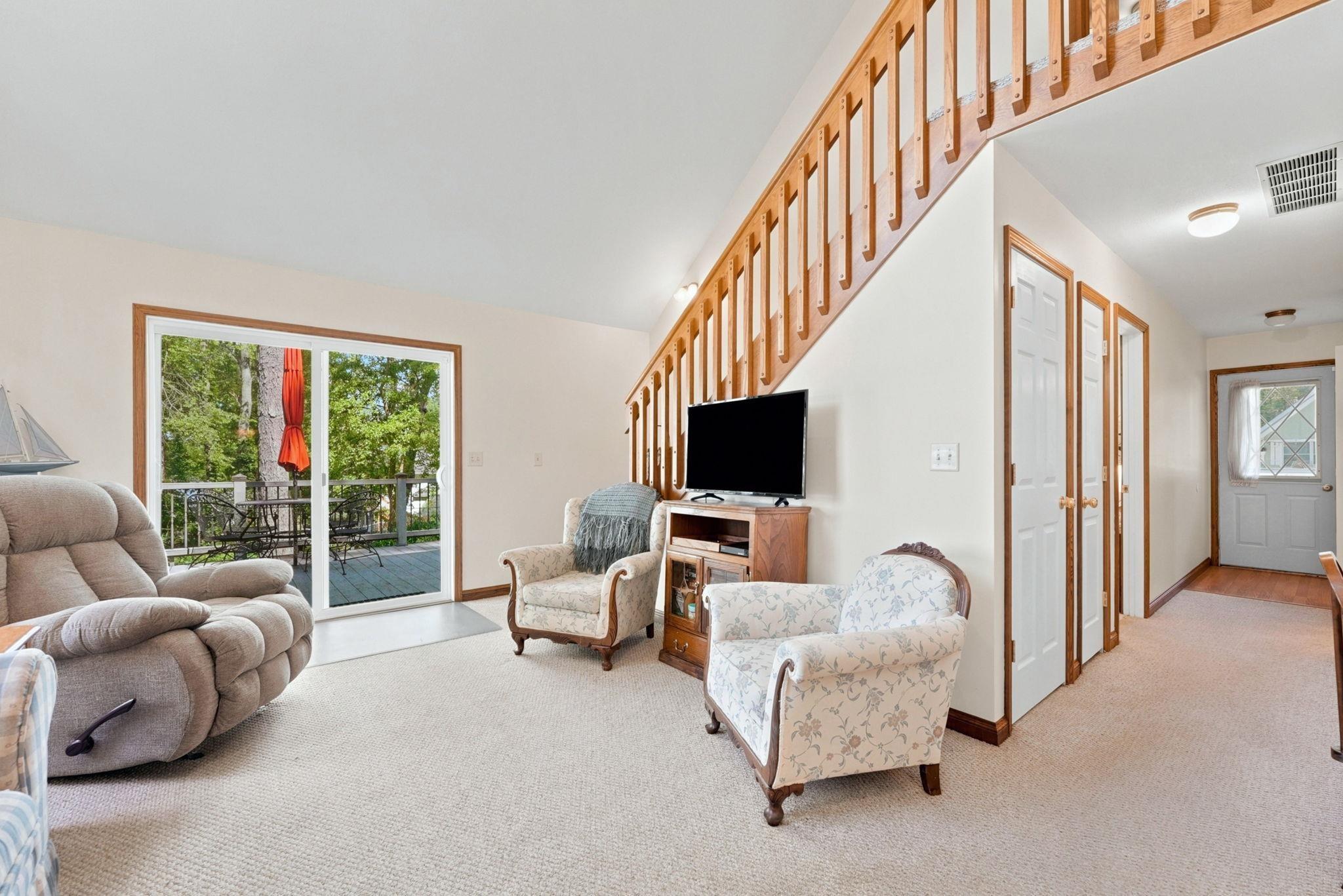 Image 3: Living area featuring light carpeting, a wood-finish staircase, and white trim, Living Room Image 3: Living area featuring light carpeting, a wood-finish staircase, and white trim, Living Room