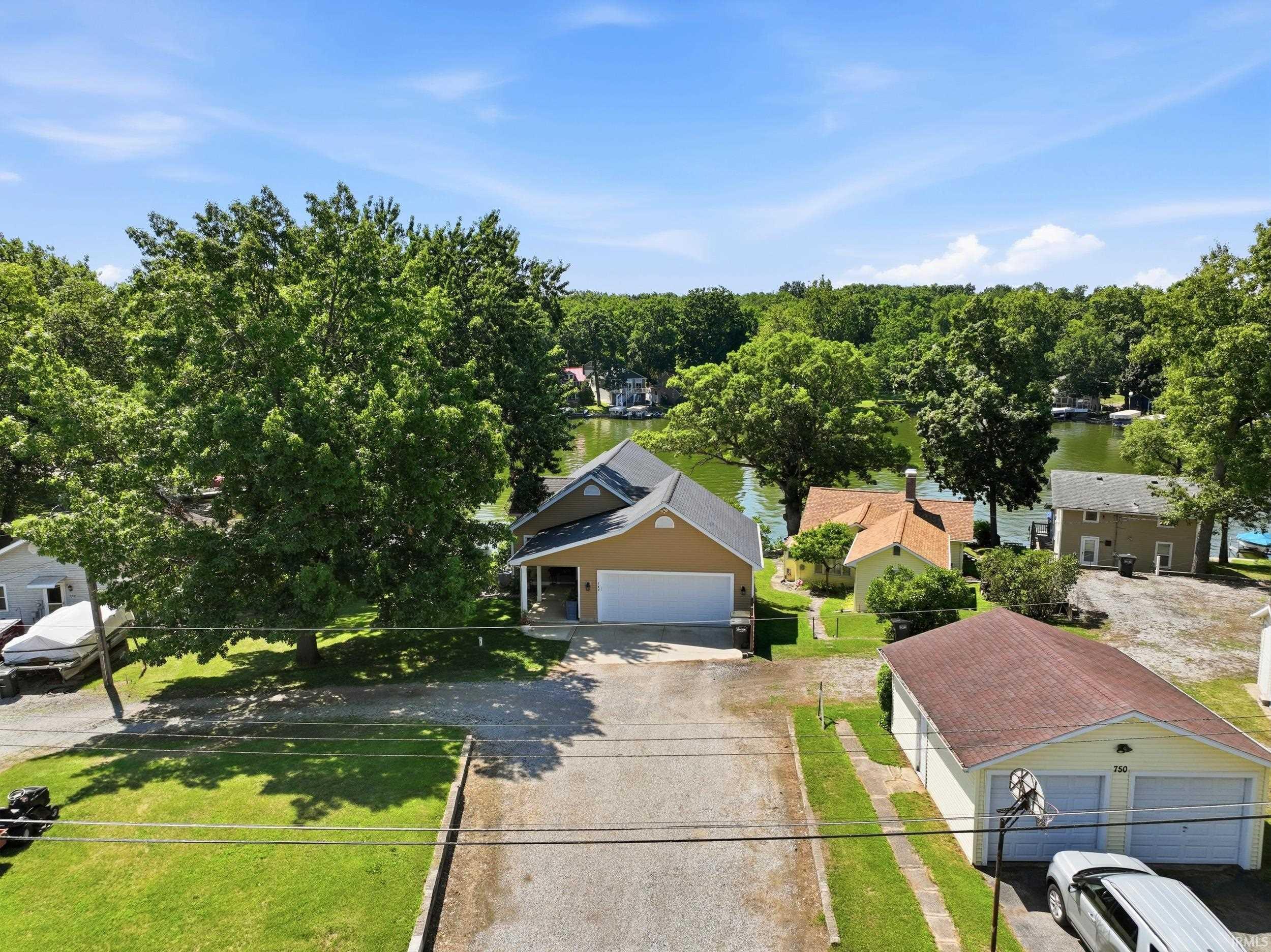 Image 2: Charming residential home featuring a spacious driveway, attached garage with neutral-tone siding, and a manicured front lawn shaded by mature trees, Aerial View Image 2: Charming residential home featuring a spacious driveway, attached garage with neutral-tone siding, and a manicured front lawn shaded by mature trees, Aerial View