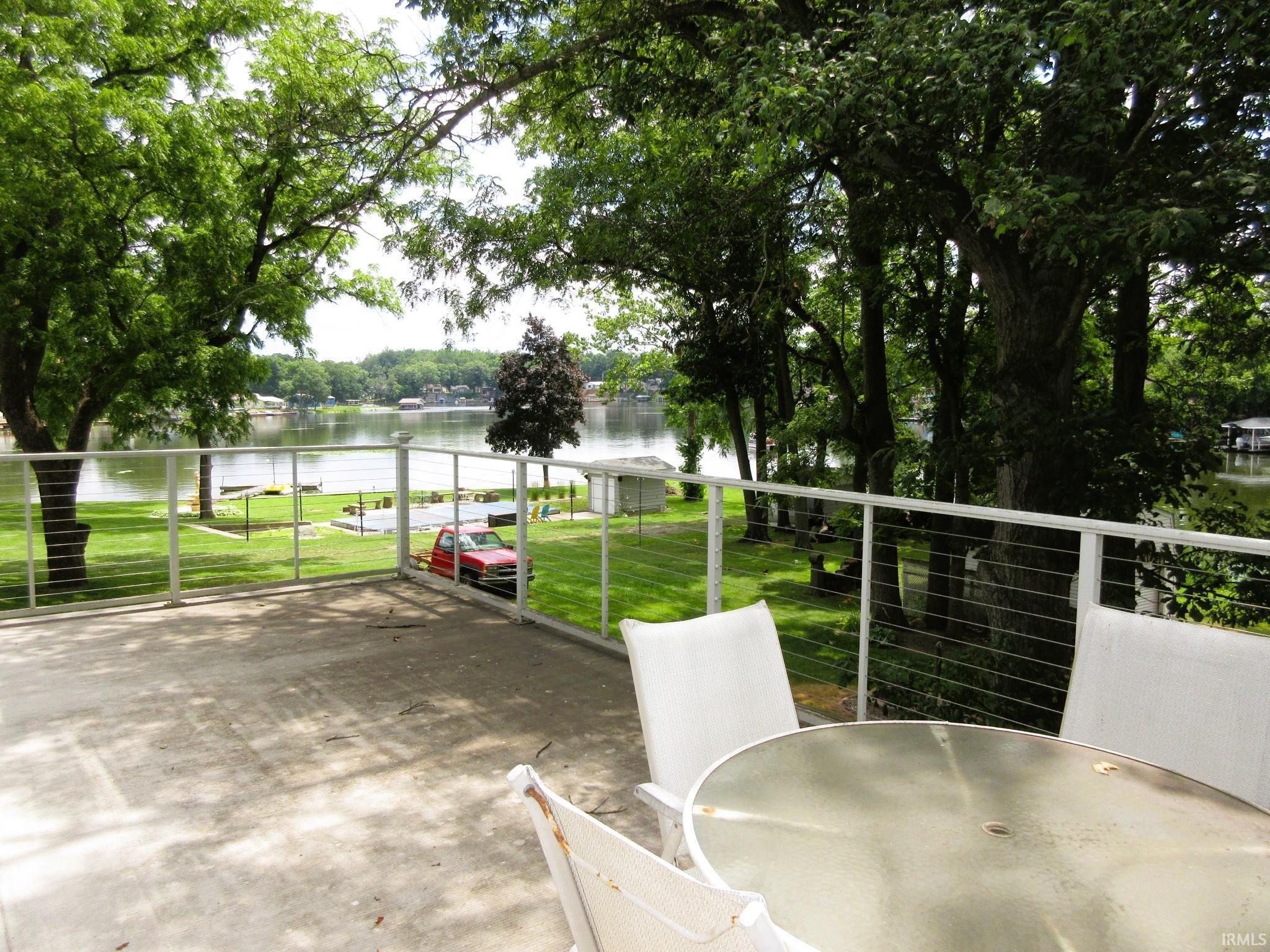 Image 2: Concrete patio with white railing and cable infill, overlooking a body of water, Second Story Roof Deck