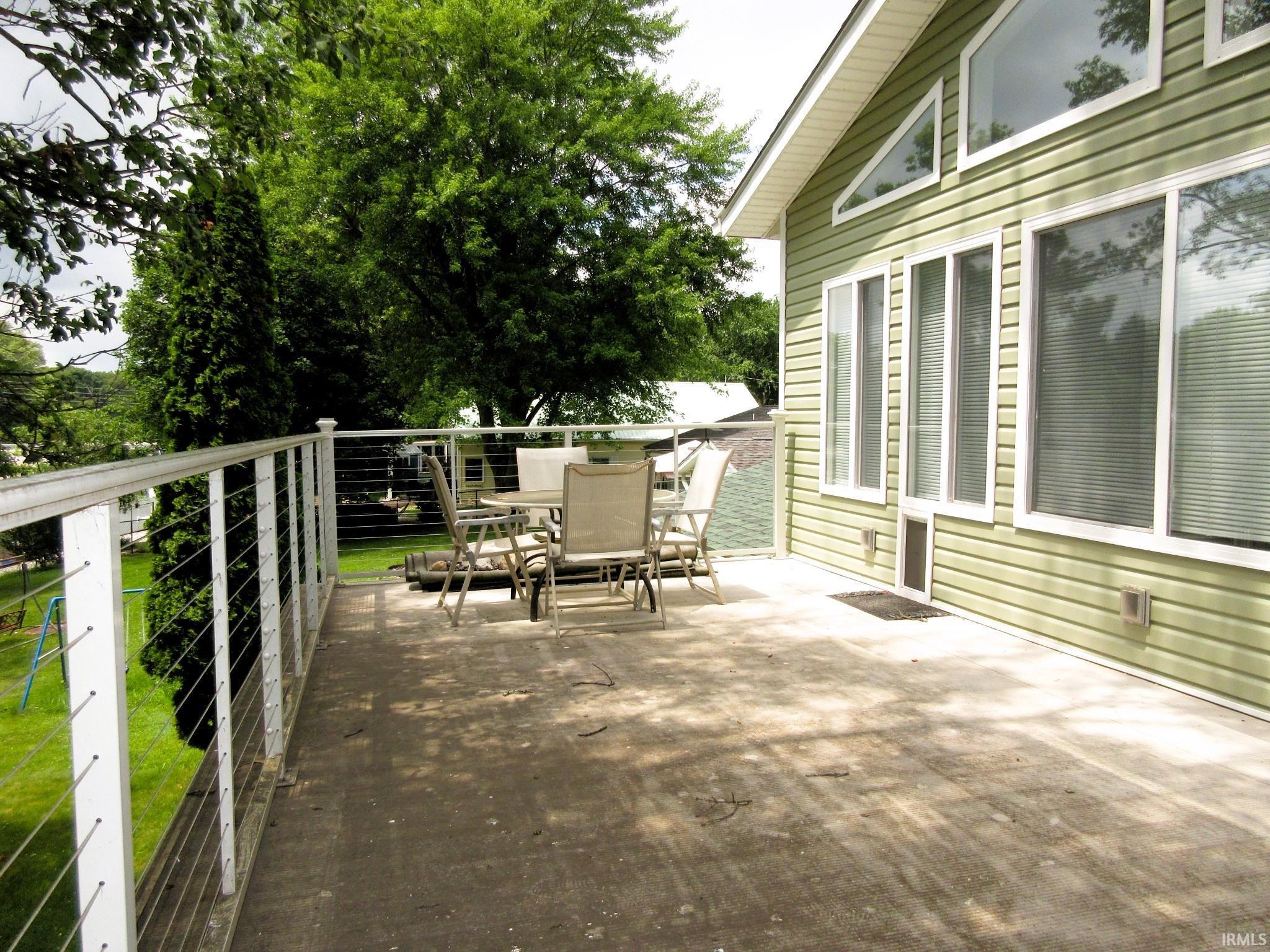 Image 3: Spacious outdoor deck with cable railing and a view of the surrounding trees, Second Story Roof Deck v 2
