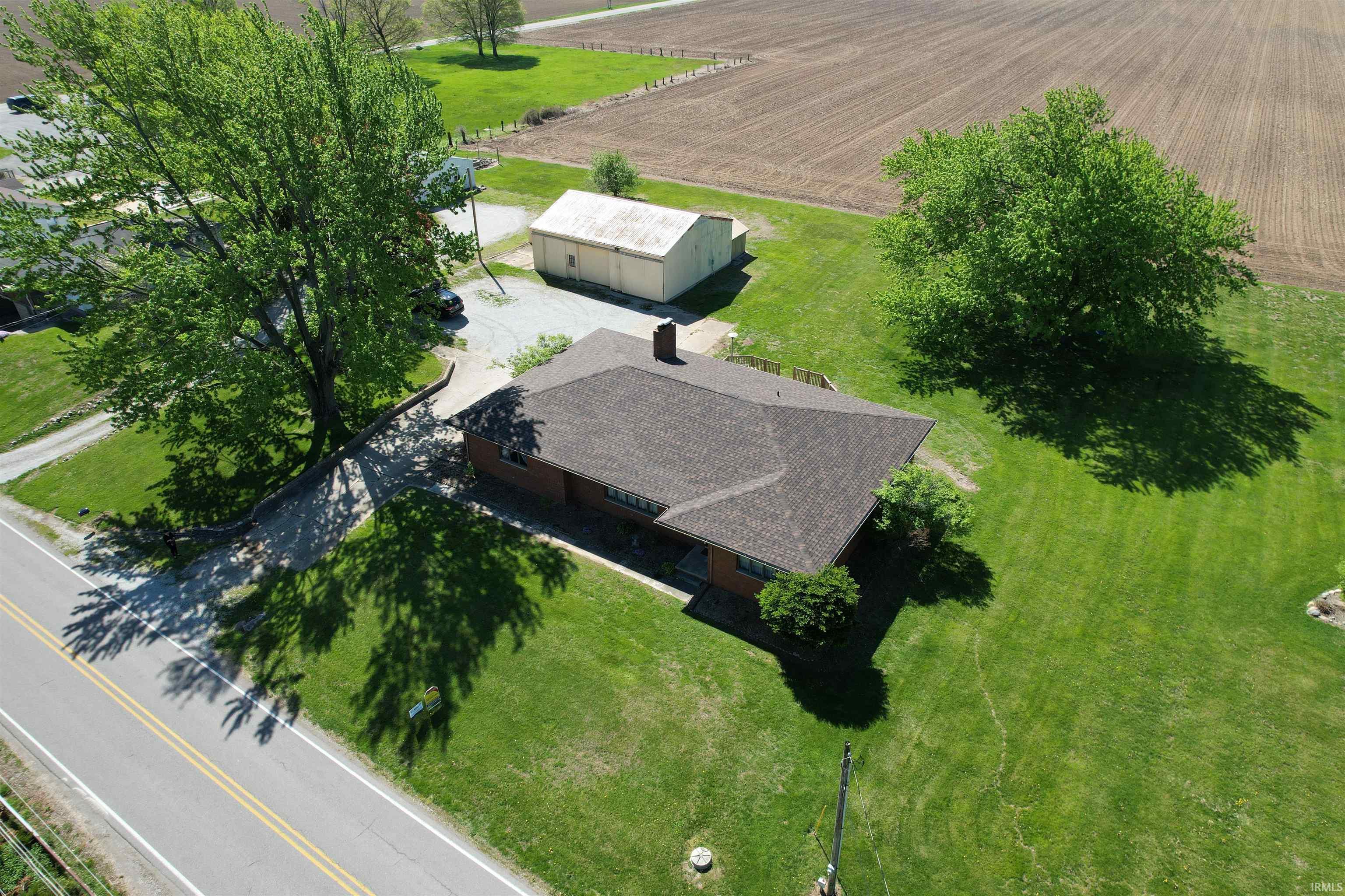 Image 2: Single-story residence with a dark shingle roof, expansive green lawn, and mature trees, Aerial View Image 2: Single-story residence with a dark shingle roof, expansive green lawn, and mature trees, Aerial View