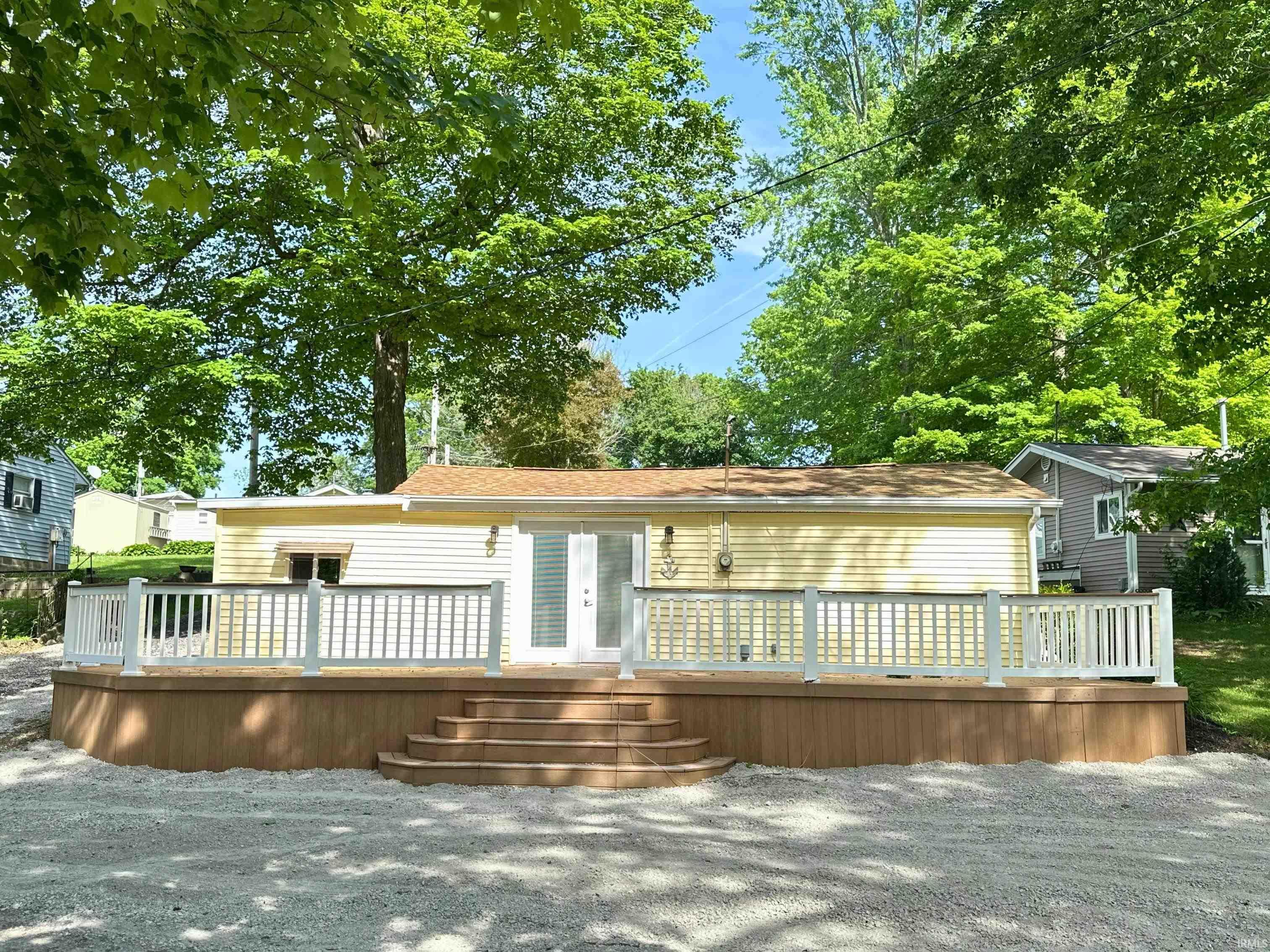 Image 0: Exterior featuring a large wood-finish deck with white railings, direct access through double doors, and a light yellow siding facade, Back Of Structure Image 0: Exterior featuring a large wood-finish deck with white railings, direct access through double doors, and a light yellow siding facade, Back Of Structure