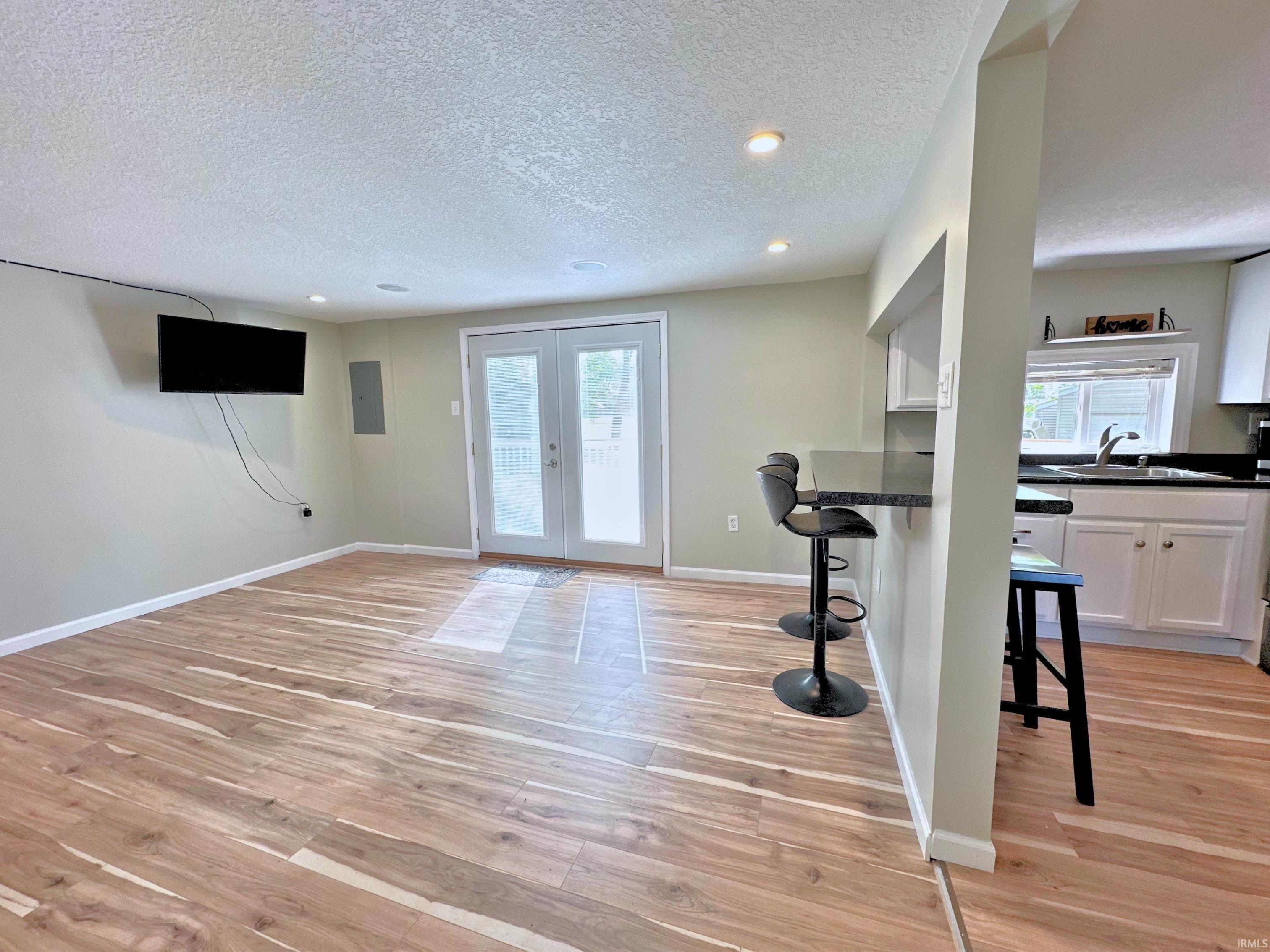 Image 1: Open-concept living area with wood flooring, recessed lighting, in-house surround sound, and direct patio access through double French doors. Entertain guests through the breakfast counter and pass-through., Living Image 1: Open-concept living area with wood flooring, recessed lighting, in-house surround sound, and direct patio access through double French doors. Entertain guests through the breakfast counter and pass-through., Living