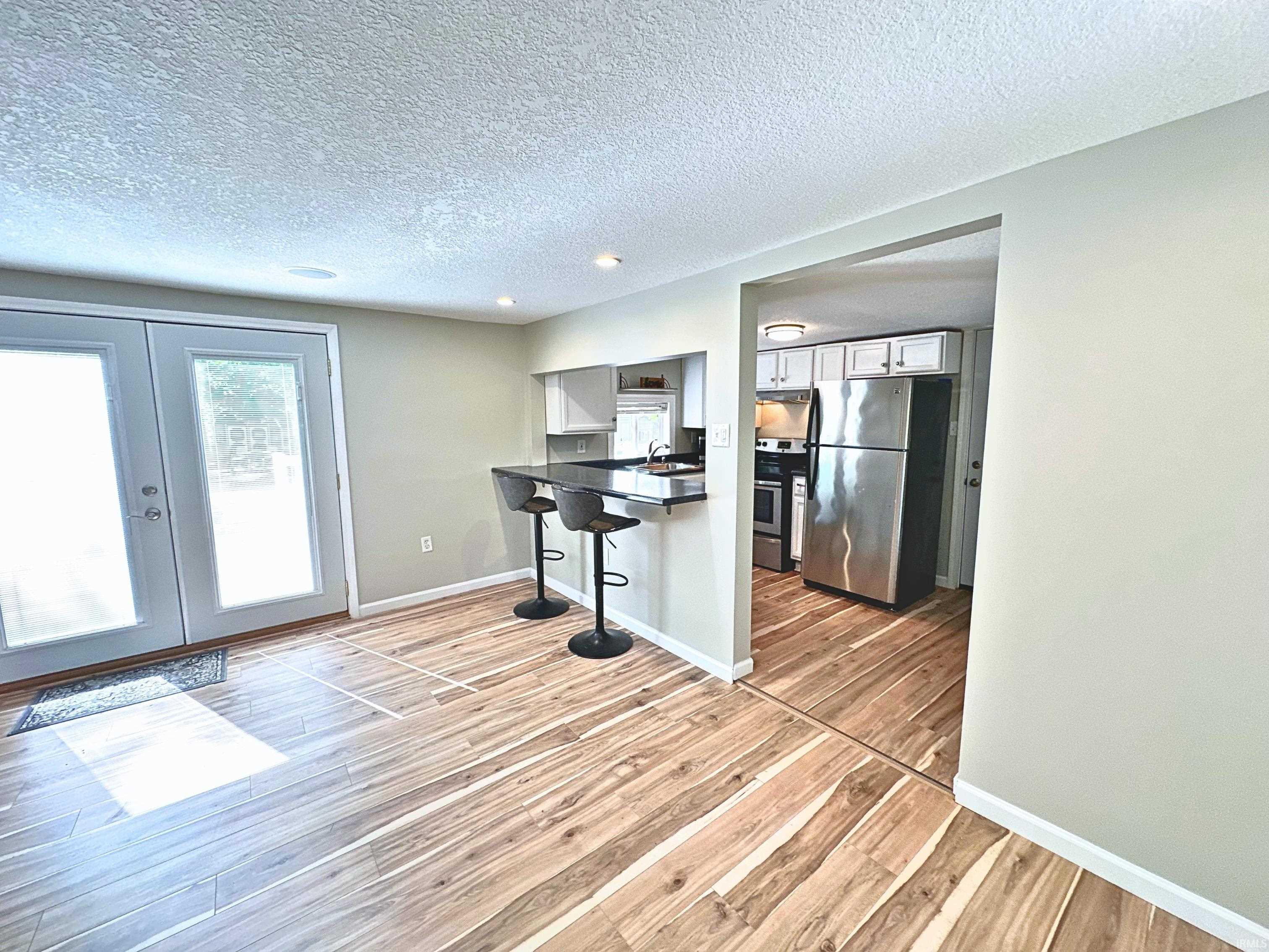 Image 2: Wood-finish flooring throughout, featuring a kitchen pass-through with a breakfast bar, new white cabinetry, and stainless steel appliances!, Kitchen Nook Image 2: Wood-finish flooring throughout, featuring a kitchen pass-through with a breakfast bar, new white cabinetry, and stainless steel appliances!, Kitchen Nook