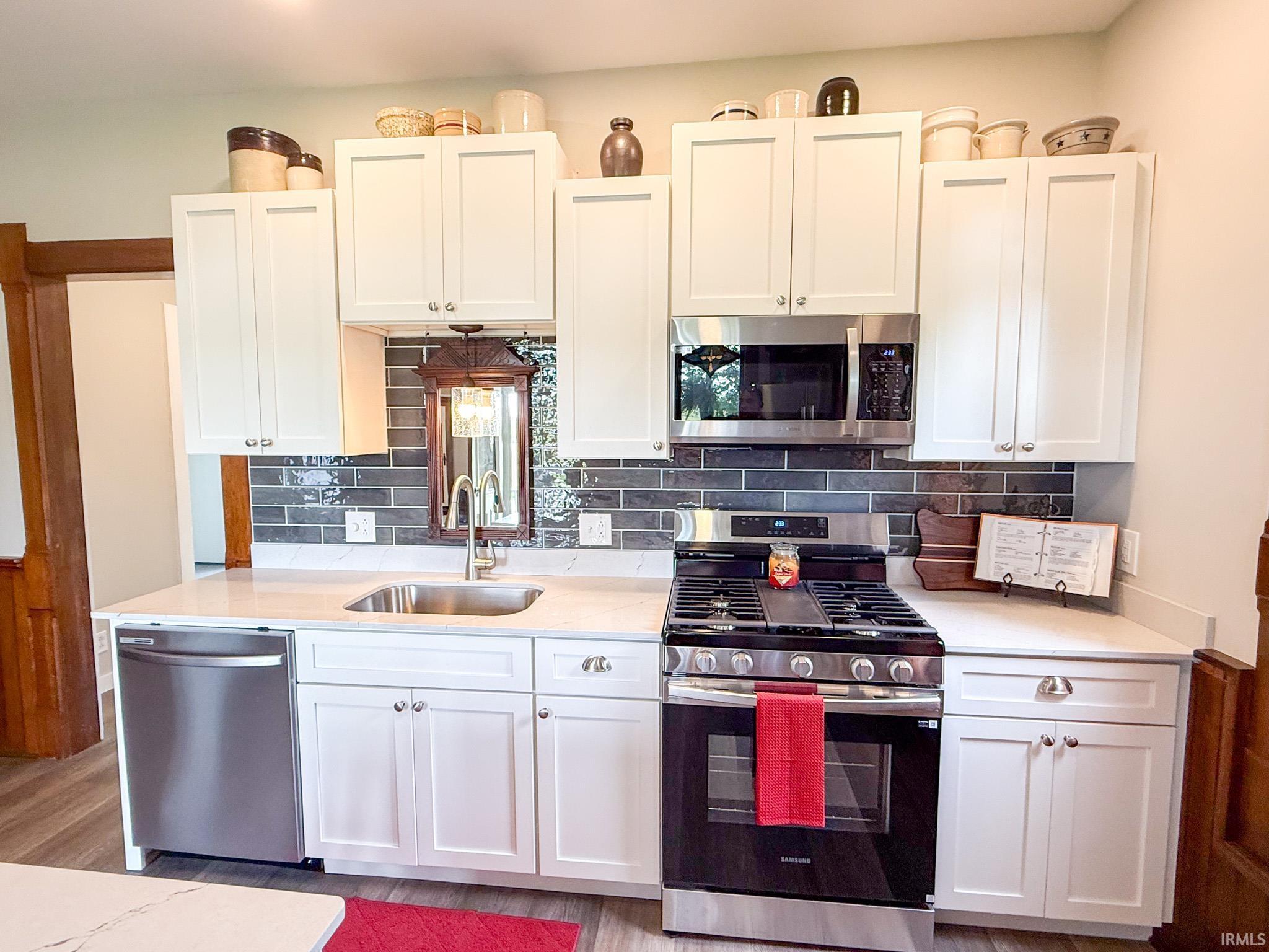 Image 3: Modern kitchen featuring white shaker cabinetry, stainless steel appliances, a gas range, a single basin sink, and wood-finish flooring, Kitchen Image 3: Modern kitchen featuring white shaker cabinetry, stainless steel appliances, a gas range, a single basin sink, and wood-finish flooring, Kitchen
