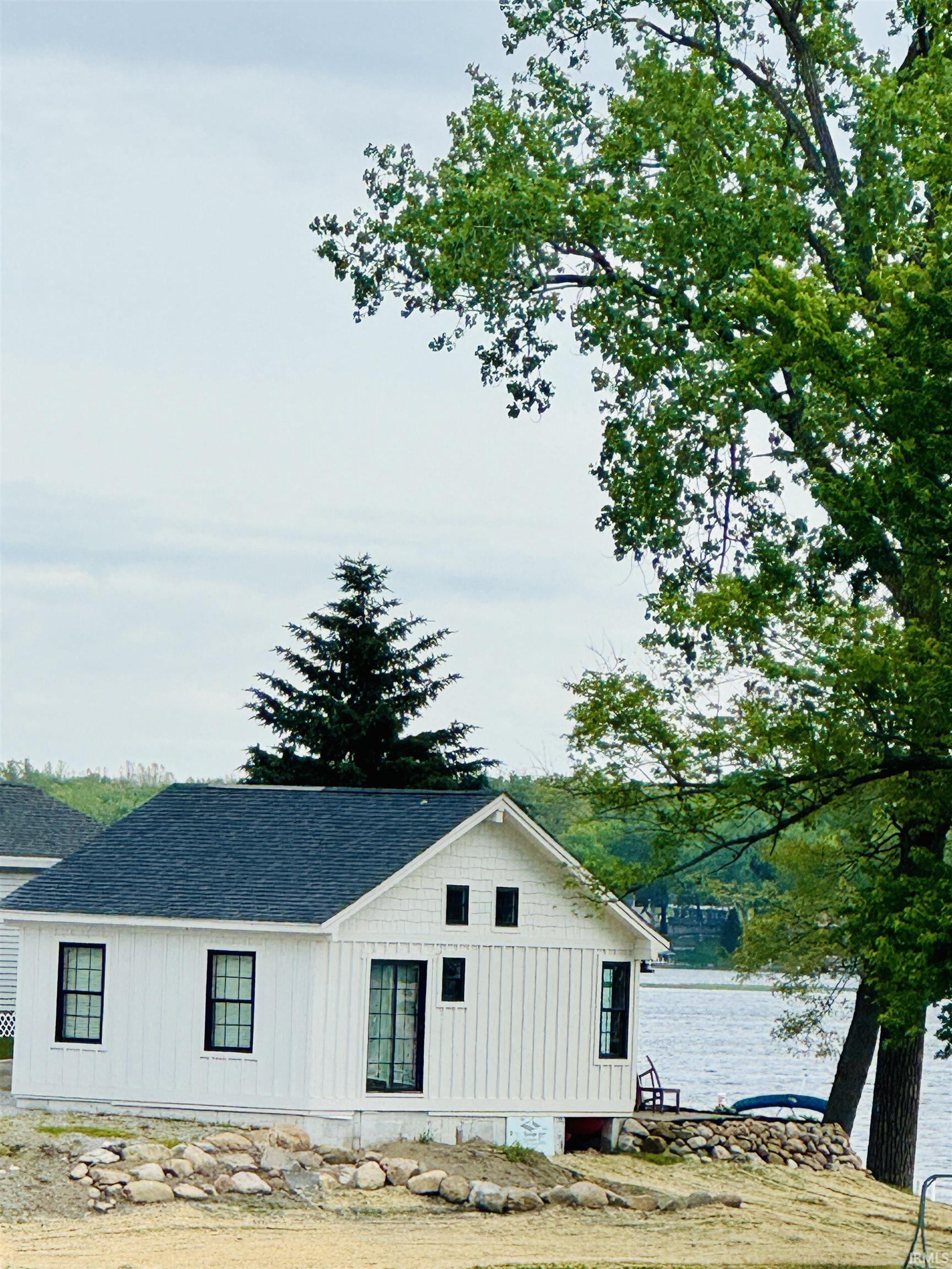 Image 0: White exterior siding with a dark shingle roof and black framed windows, Side Of Structure Image 0: White exterior siding with a dark shingle roof and black framed windows, Side Of Structure