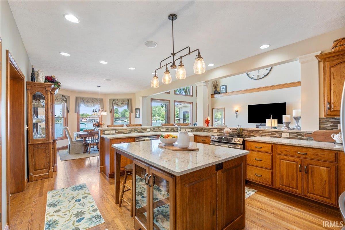 Image 2: Open-concept kitchen featuring wood-finish flooring, recessed lighting, a central island with a quartz countertop, and elevated breakfast bar, Island Kitchen Image 2: Open-concept kitchen featuring wood-finish flooring, recessed lighting, a central island with a quartz countertop, and elevated breakfast bar, Island Kitchen