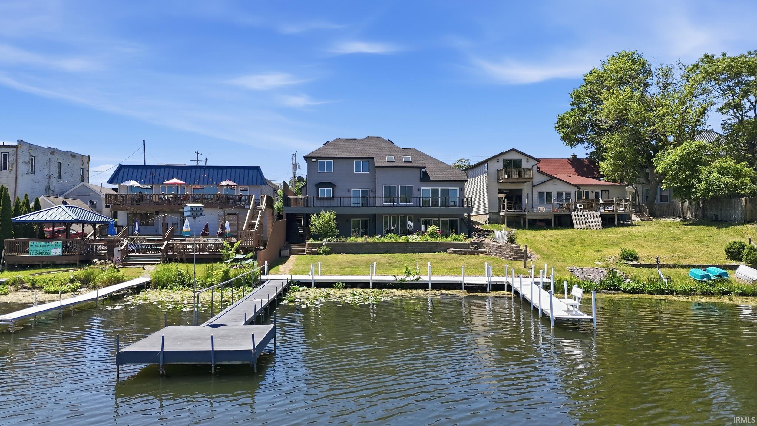 Image 2: Waterfront property featuring multiple private docks, tiered wooden decking, and a gray-sided residence with multiple windows, Dock Image 2: Waterfront property featuring multiple private docks, tiered wooden decking, and a gray-sided residence with multiple windows, Dock