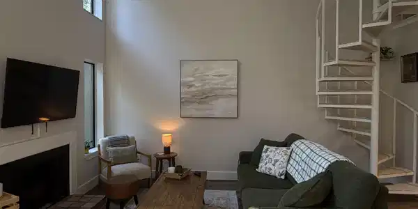 Image 2: Living area featuring a white spiral staircase and a fireplace with a tiled hearth, Living Room