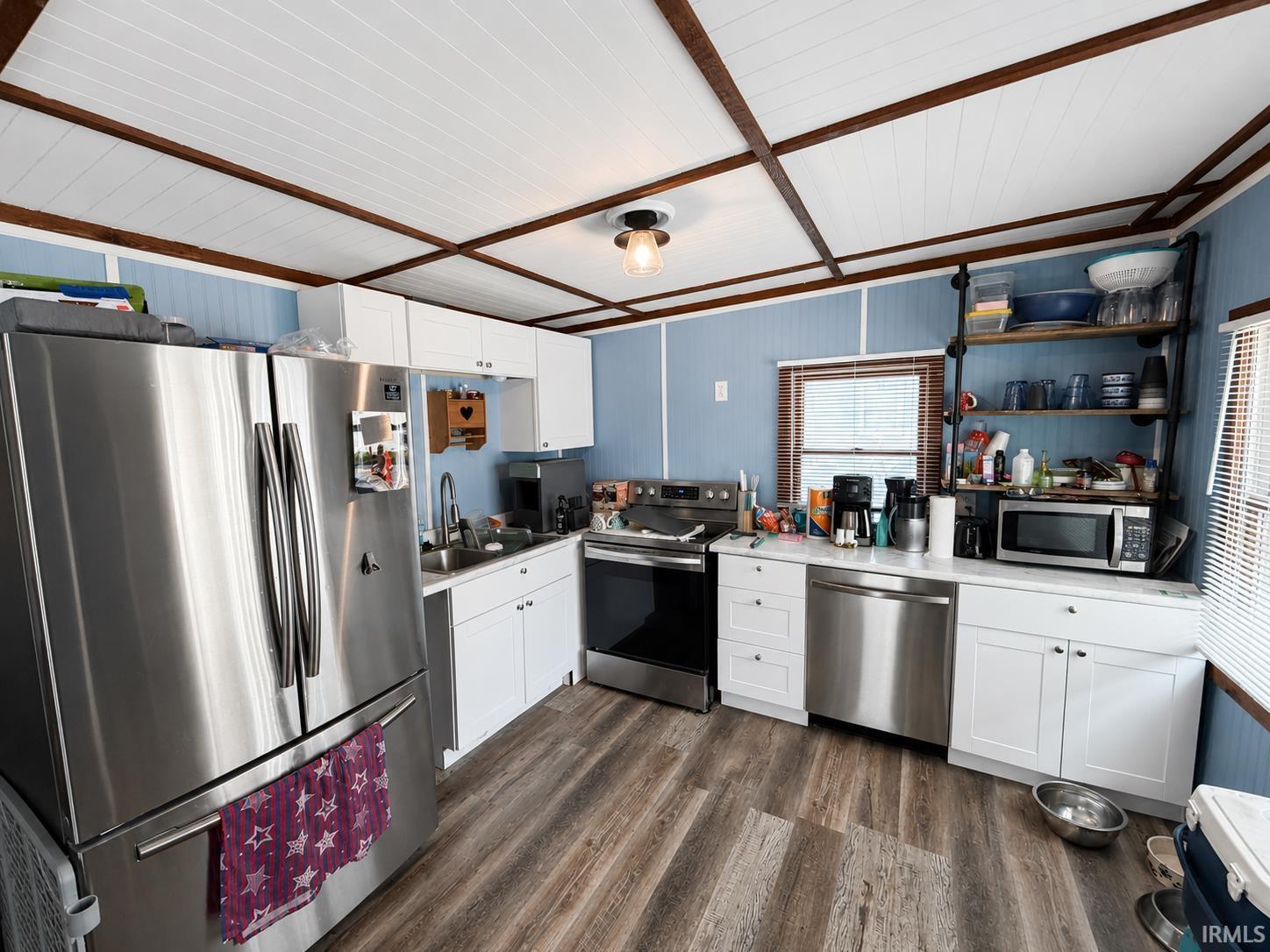 Image 2: Kitchen featuring wood-finish flooring, white cabinetry, a stainless steel refrigerator, and a stainless steel dishwasher, Kitchen Image 2: Kitchen featuring wood-finish flooring, white cabinetry, a stainless steel refrigerator, and a stainless steel dishwasher, Kitchen