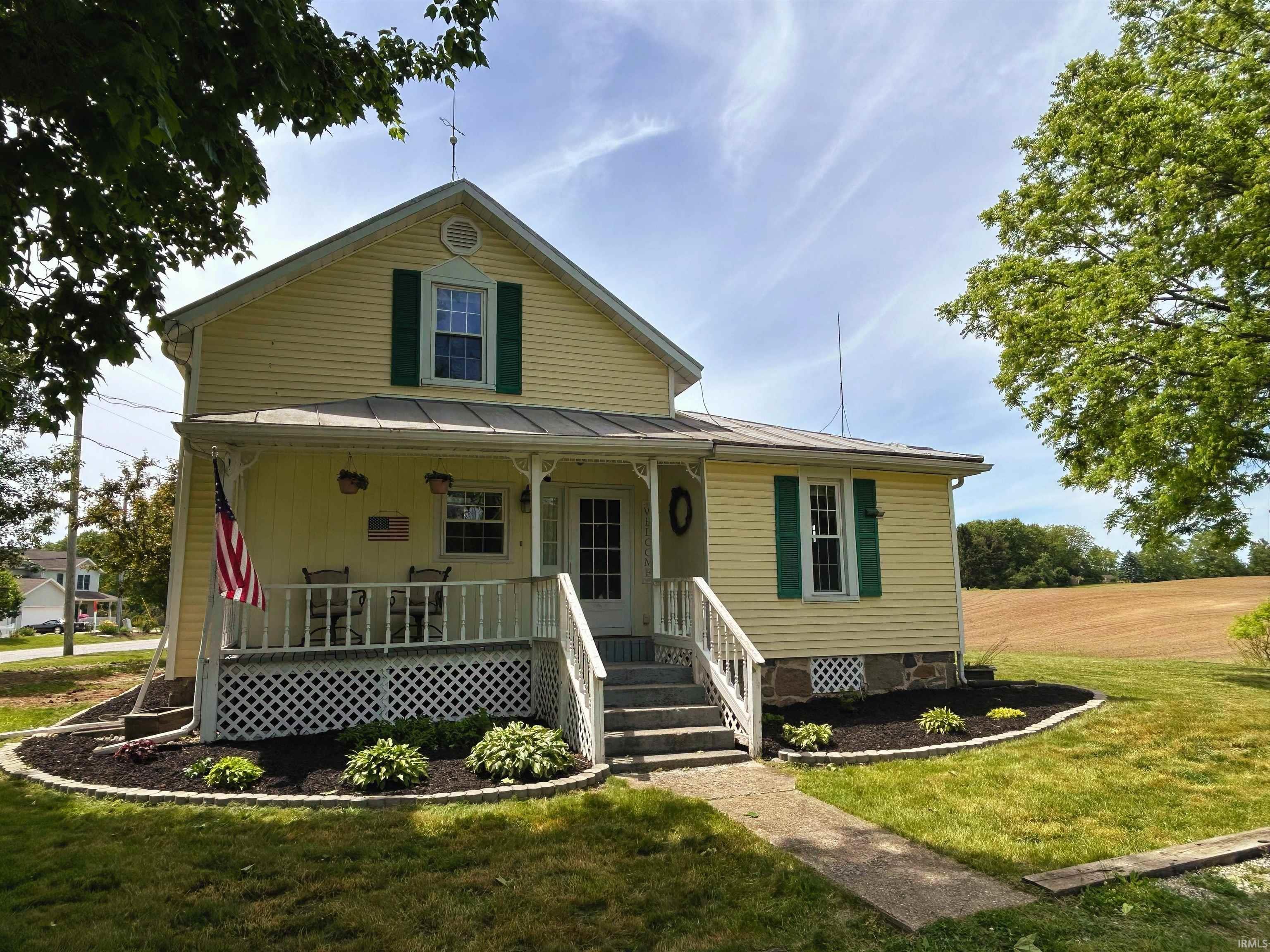 Image 0: Yellow siding exterior with green window shutters, a covered front porch, and a concrete walkway, Front Of Structure Image 0: Yellow siding exterior with green window shutters, a covered front porch, and a concrete walkway, Front Of Structure