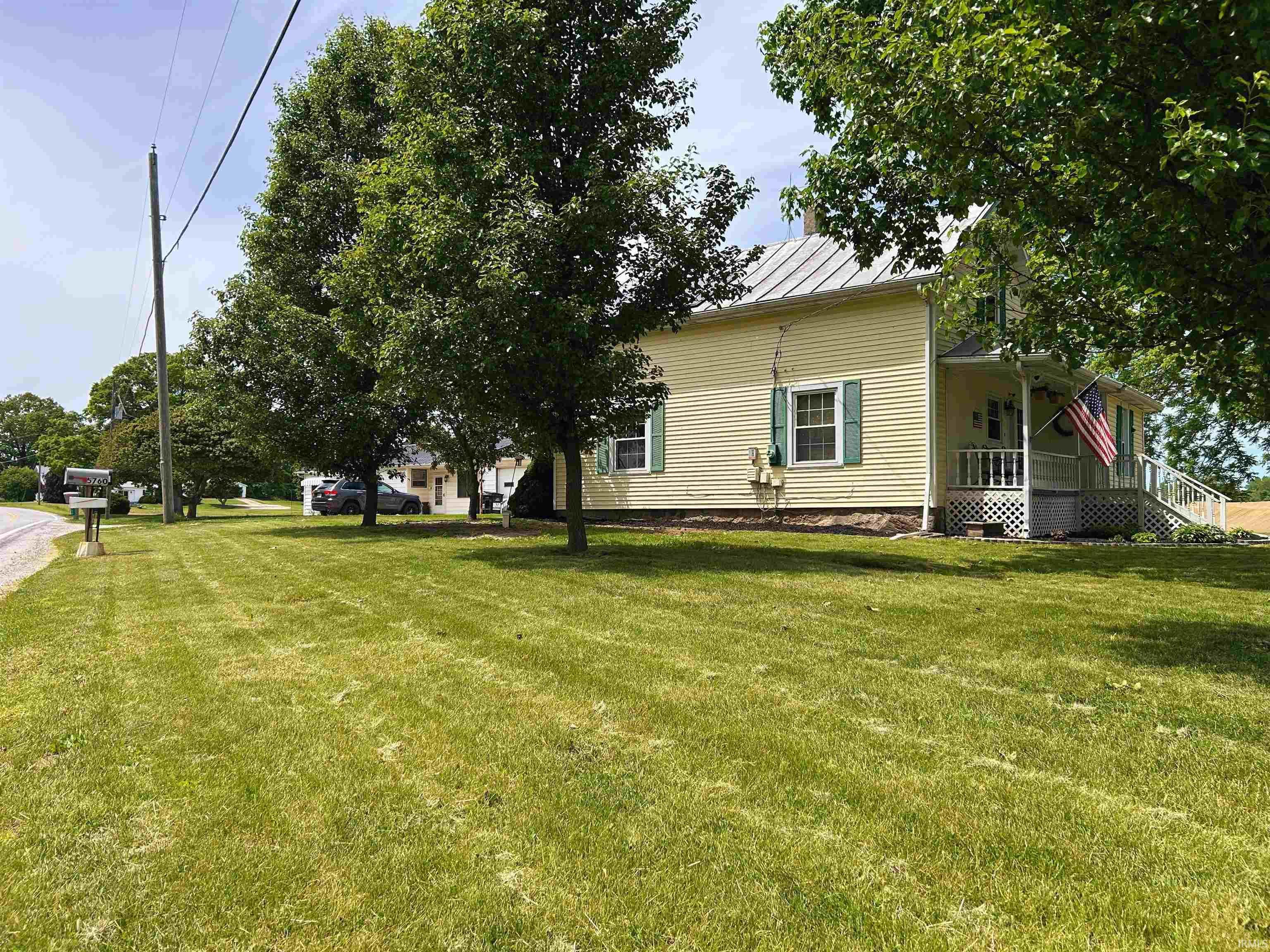 Image 1: Yellow siding residence featuring a metal roof, white trim, and contrasting green shutters, Side Of Structure Image 1: Yellow siding residence featuring a metal roof, white trim, and contrasting green shutters, Side Of Structure