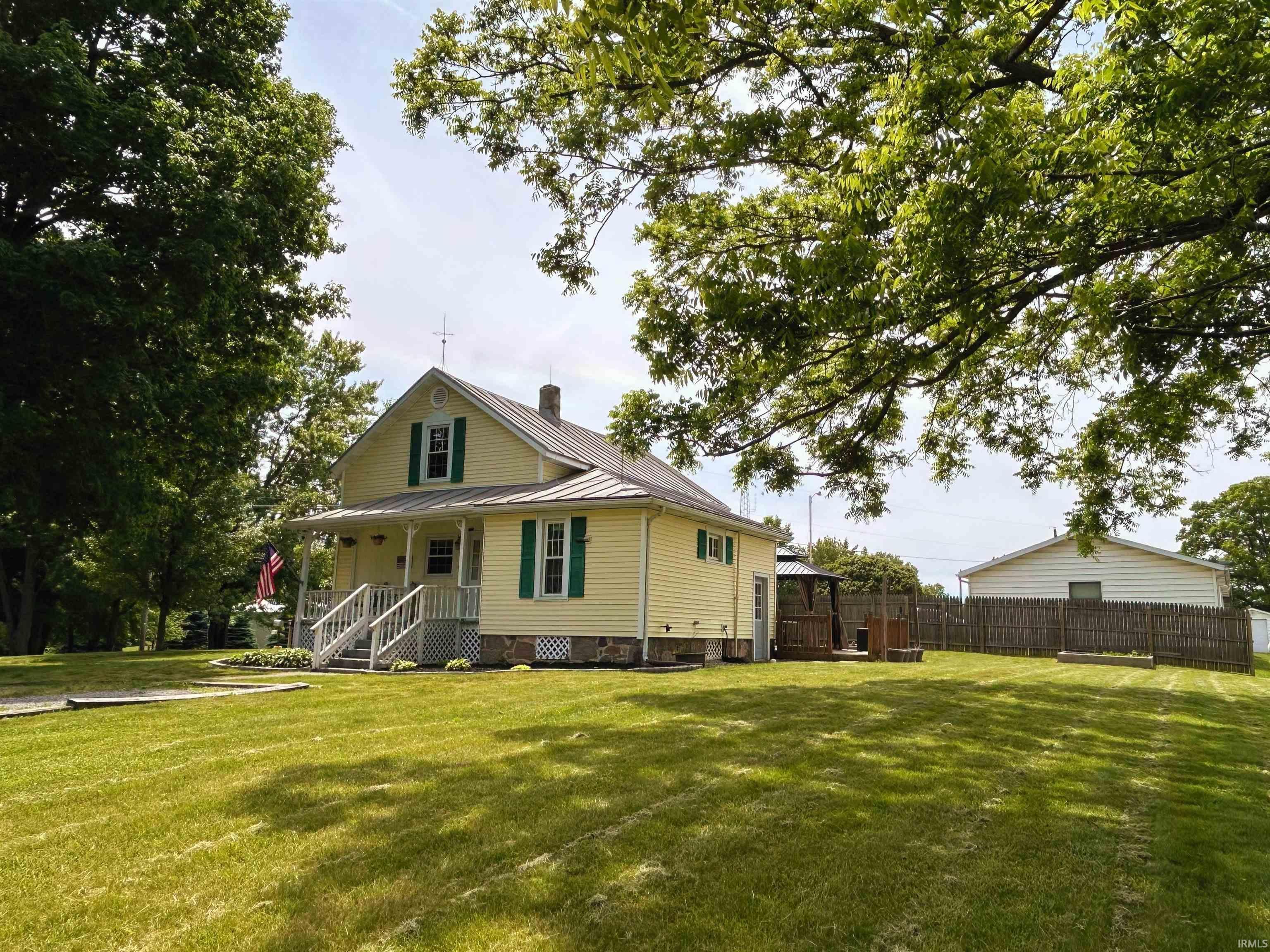Image 2: Yellow siding residence with green shutters, a covered front porch, and a metal roof, Front Of Structure Image 2: Yellow siding residence with green shutters, a covered front porch, and a metal roof, Front Of Structure