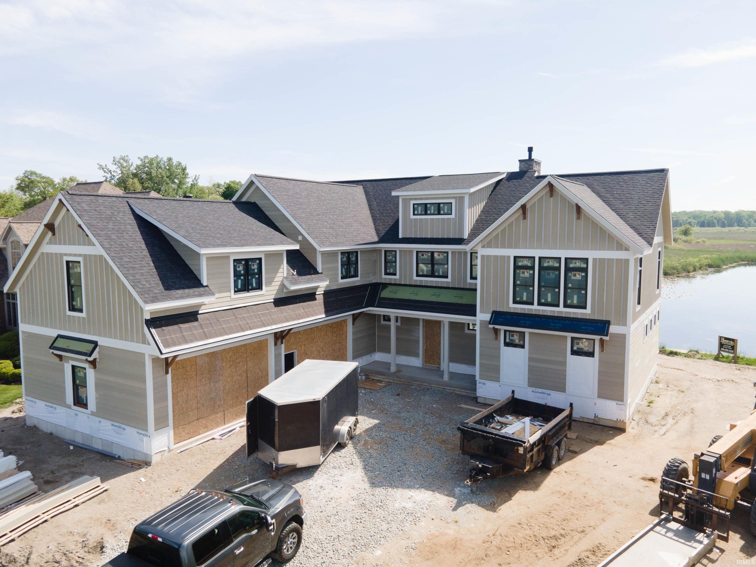 Image 0: Newly constructed residence featuring light-toned vertical and horizontal siding, a dark shingle roof, and multiple dormer windows, Front Of Structure Image 0: Newly constructed residence featuring light-toned vertical and horizontal siding, a dark shingle roof, and multiple dormer windows, Front Of Structure