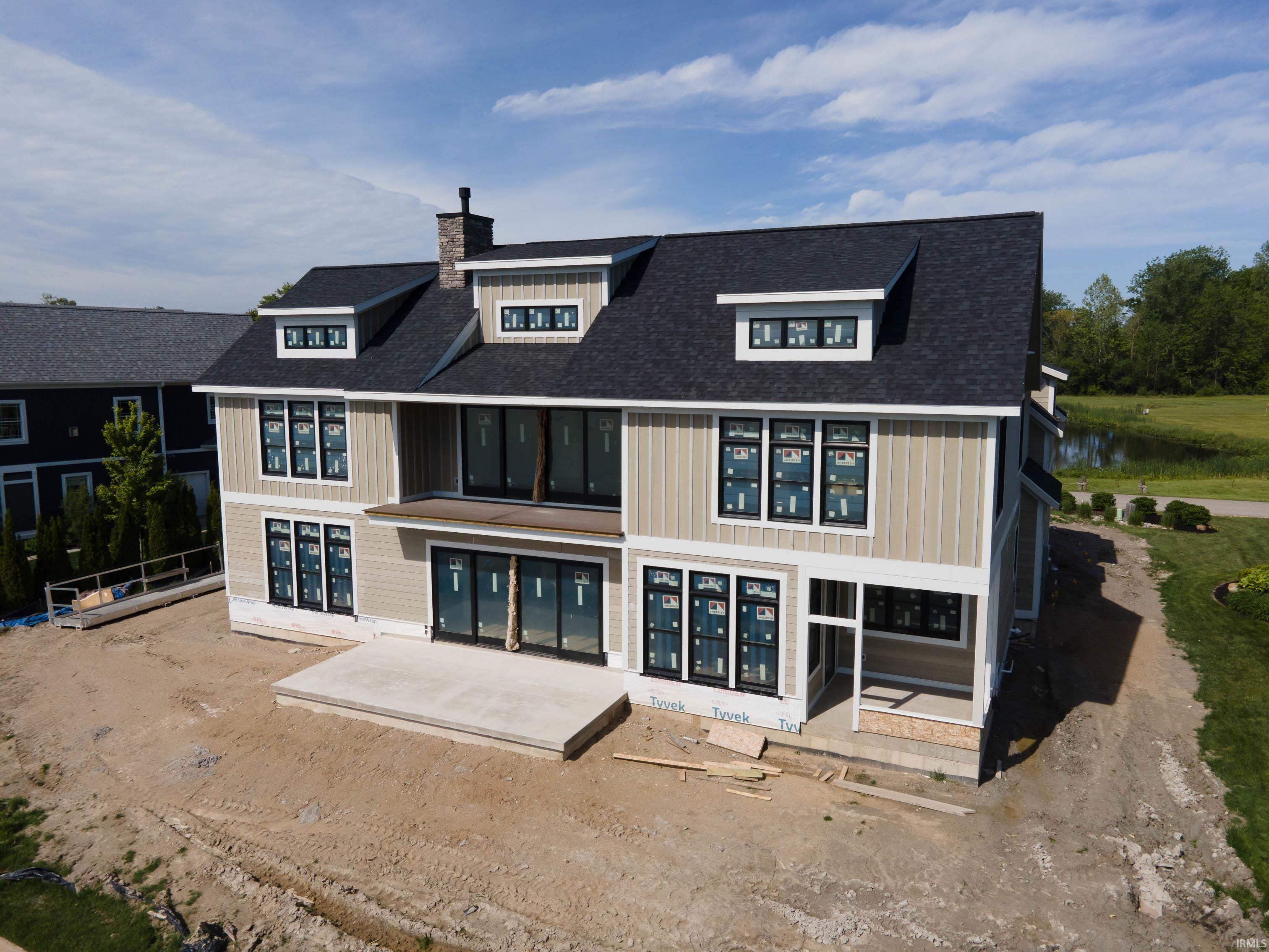 Image 3: Two-story residence featuring a dark shingle roof, light-toned vertical siding, and multiple dormer windows, Back Of Structure Image 3: Two-story residence featuring a dark shingle roof, light-toned vertical siding, and multiple dormer windows, Back Of Structure