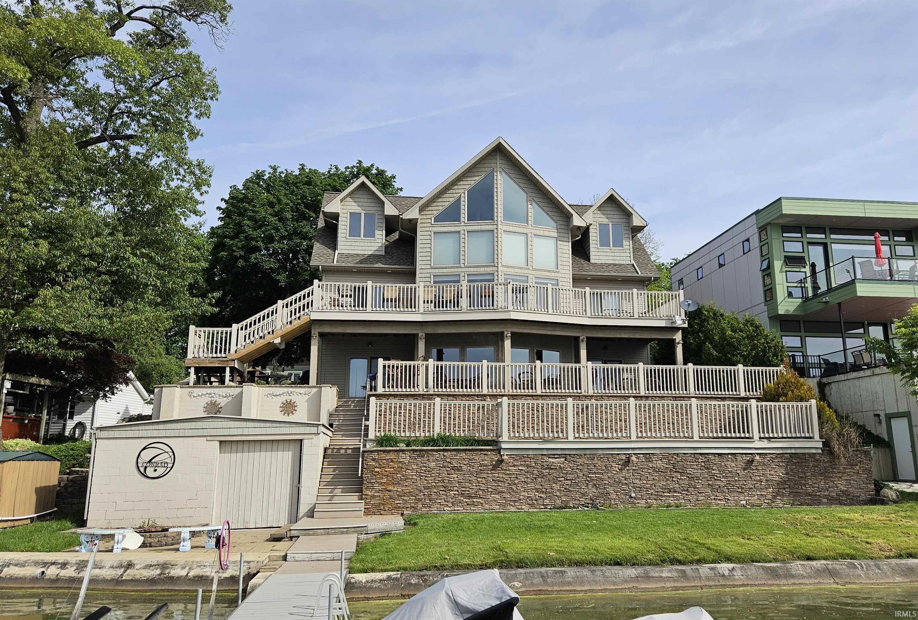 Image 0: Multi-level waterfront residence featuring extensive decking, a striking window wall, dormer windows, a boat house, and a private dock, Back Of Structure Image 0: Multi-level waterfront residence featuring extensive decking, a striking window wall, dormer windows, a boat house, and a private dock, Back Of Structure