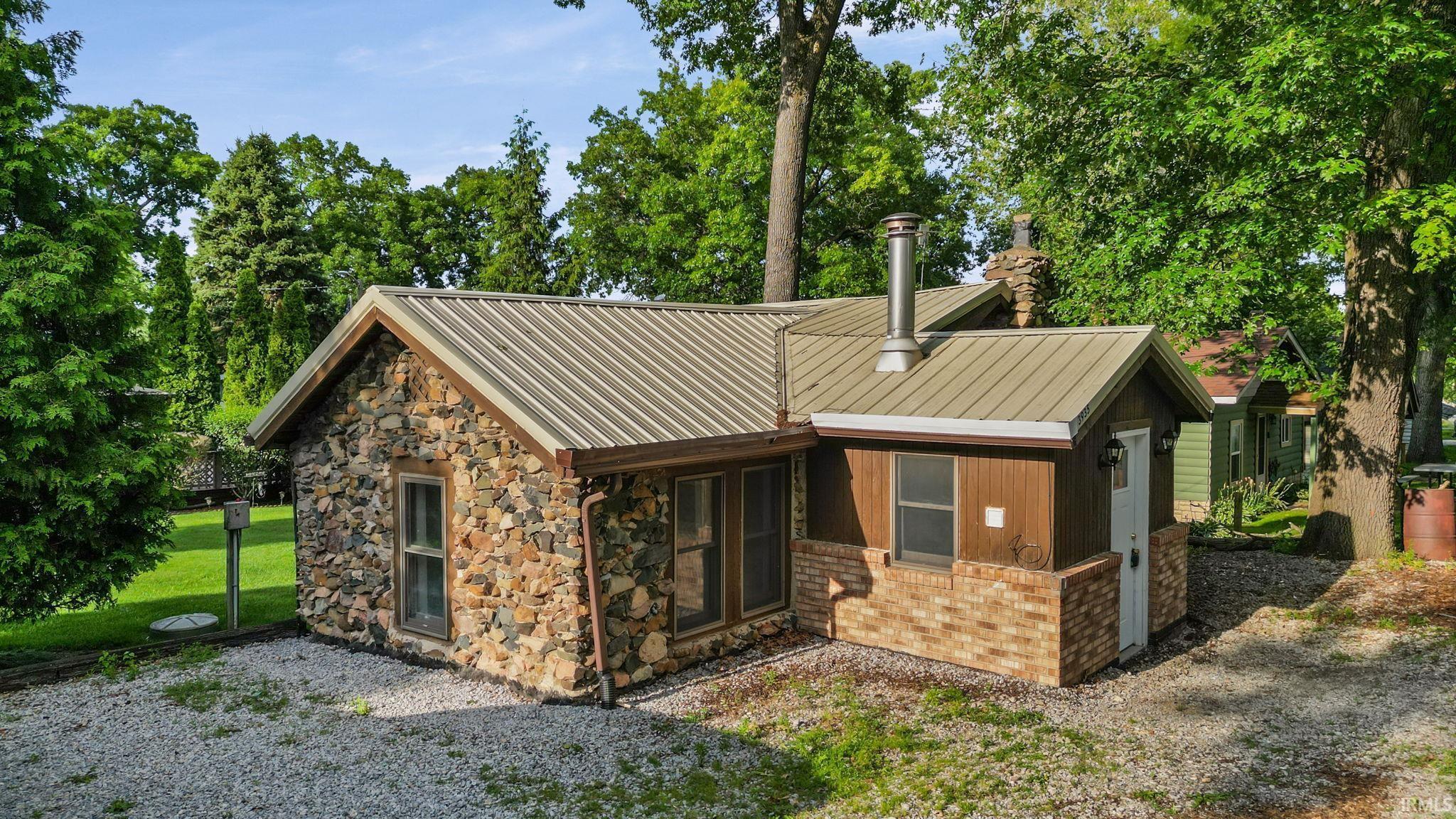 Image 1: Stone and wood siding exterior featuring a metal roof, brick accent wall, and a prominent chimney, Front Of Structure