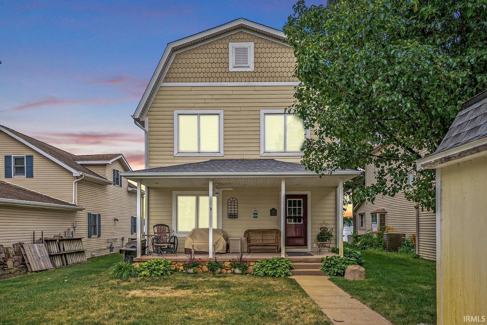 Image 3: Two-story residence featuring light yellow siding, a gambrel roofline with decorative shingles, and a covered front porch, Front Of Structure