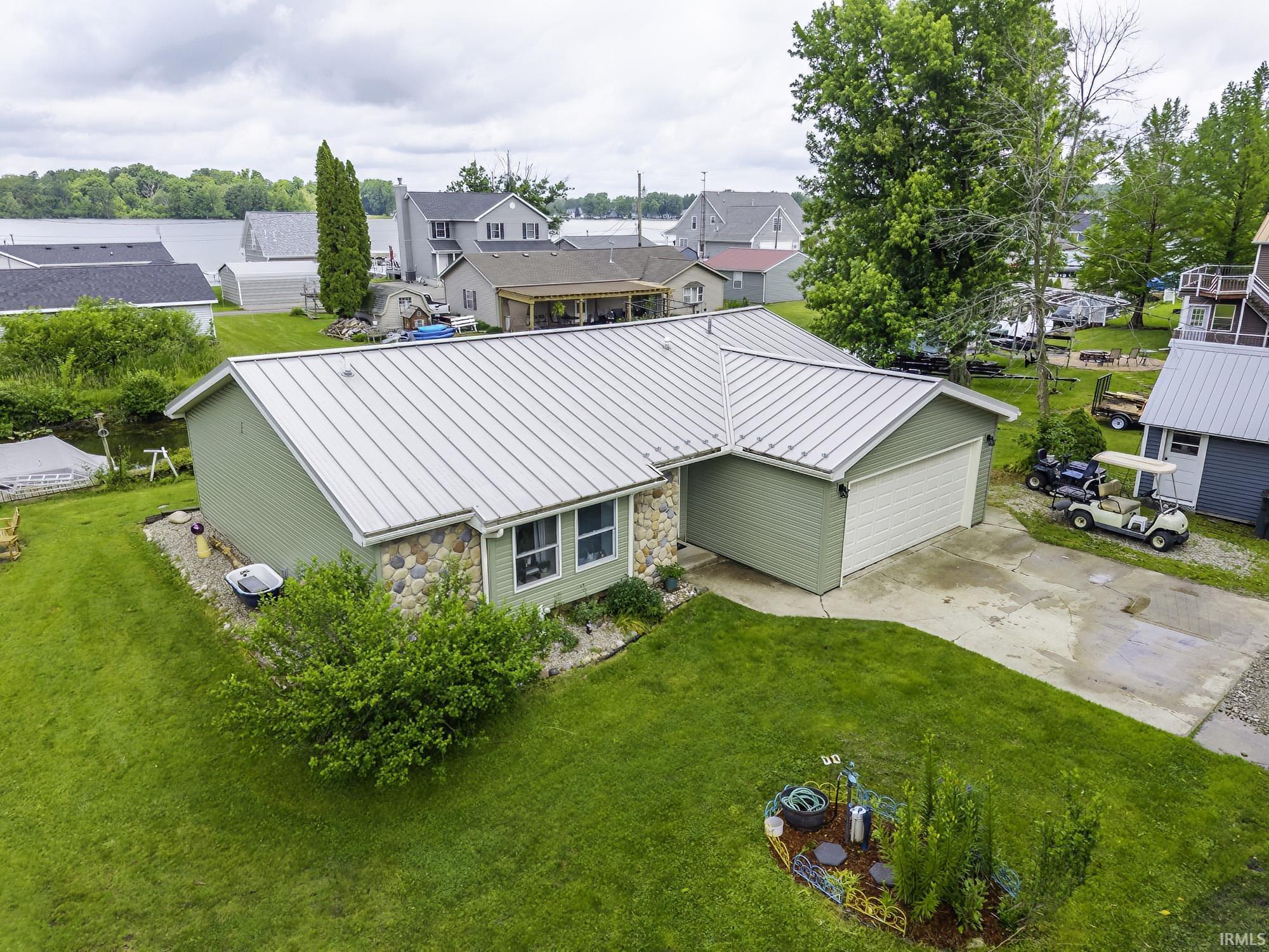 Image 3: Ranch-style residence featuring a metal roof, attached garage, and stone facade accents, Aerial View
