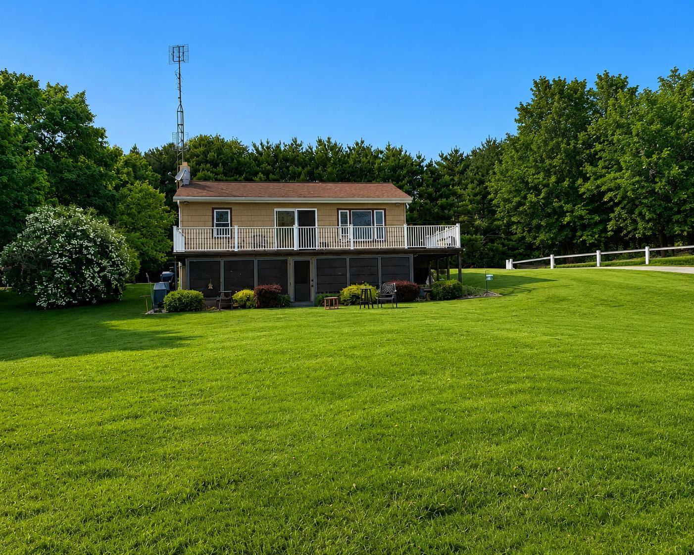 Image 1: Two-story residence featuring a ground-level patio and an upper-level balcony with white railings, Back Of Structure Image 1: Two-story residence featuring a ground-level patio and an upper-level balcony with white railings, Back Of Structure