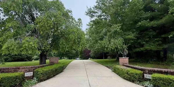 Image 2: Concrete driveway framed by mature trees, brick pillars, manicured hedges, and lush green lawns, Private Driveway entrance Image 2: Concrete driveway framed by mature trees, brick pillars, manicured hedges, and lush green lawns, Private Driveway entrance