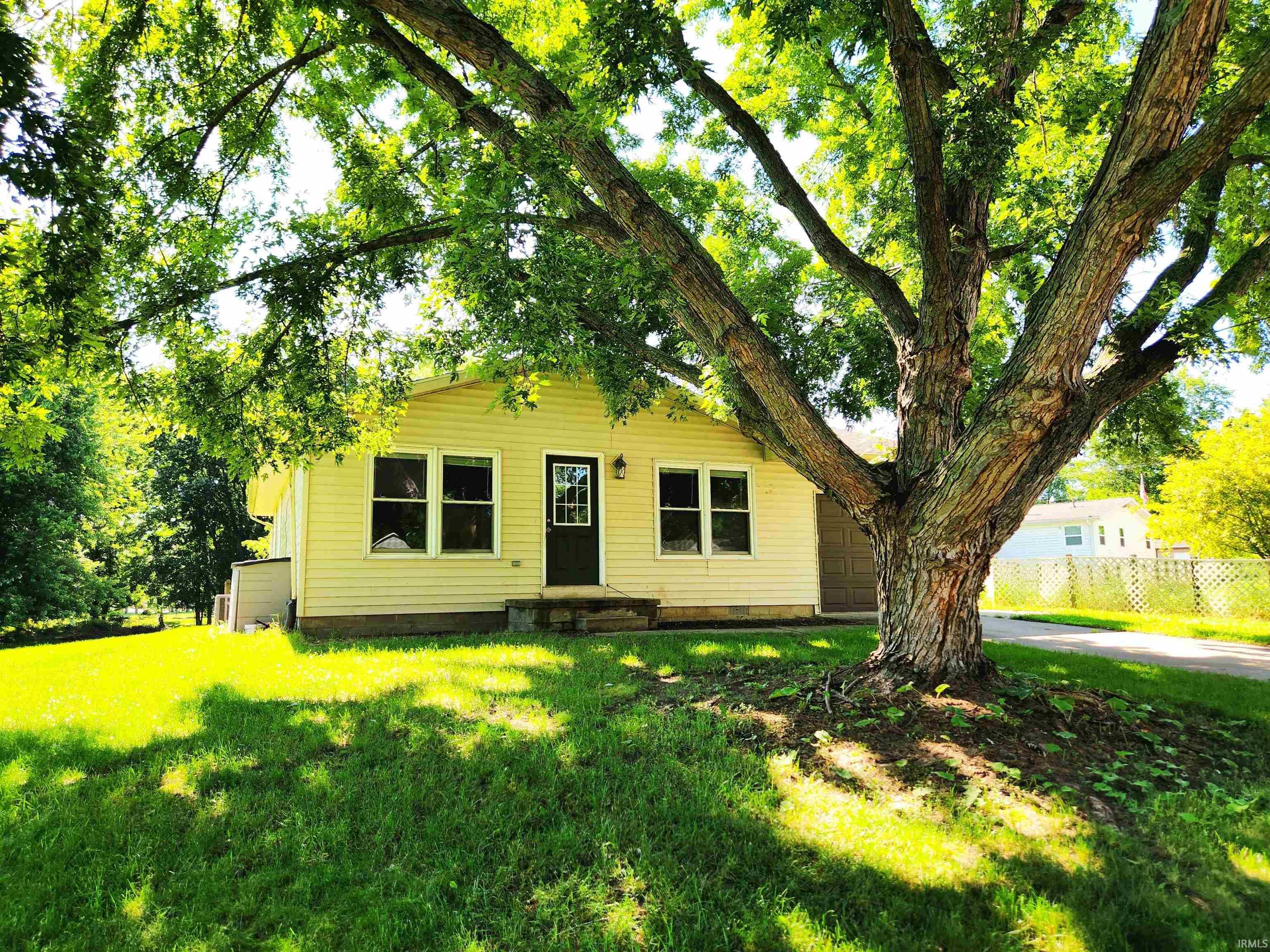 Image 3: Single-story residence featuring light yellow siding and a dark entry door with upper window pane, Front Of Structure