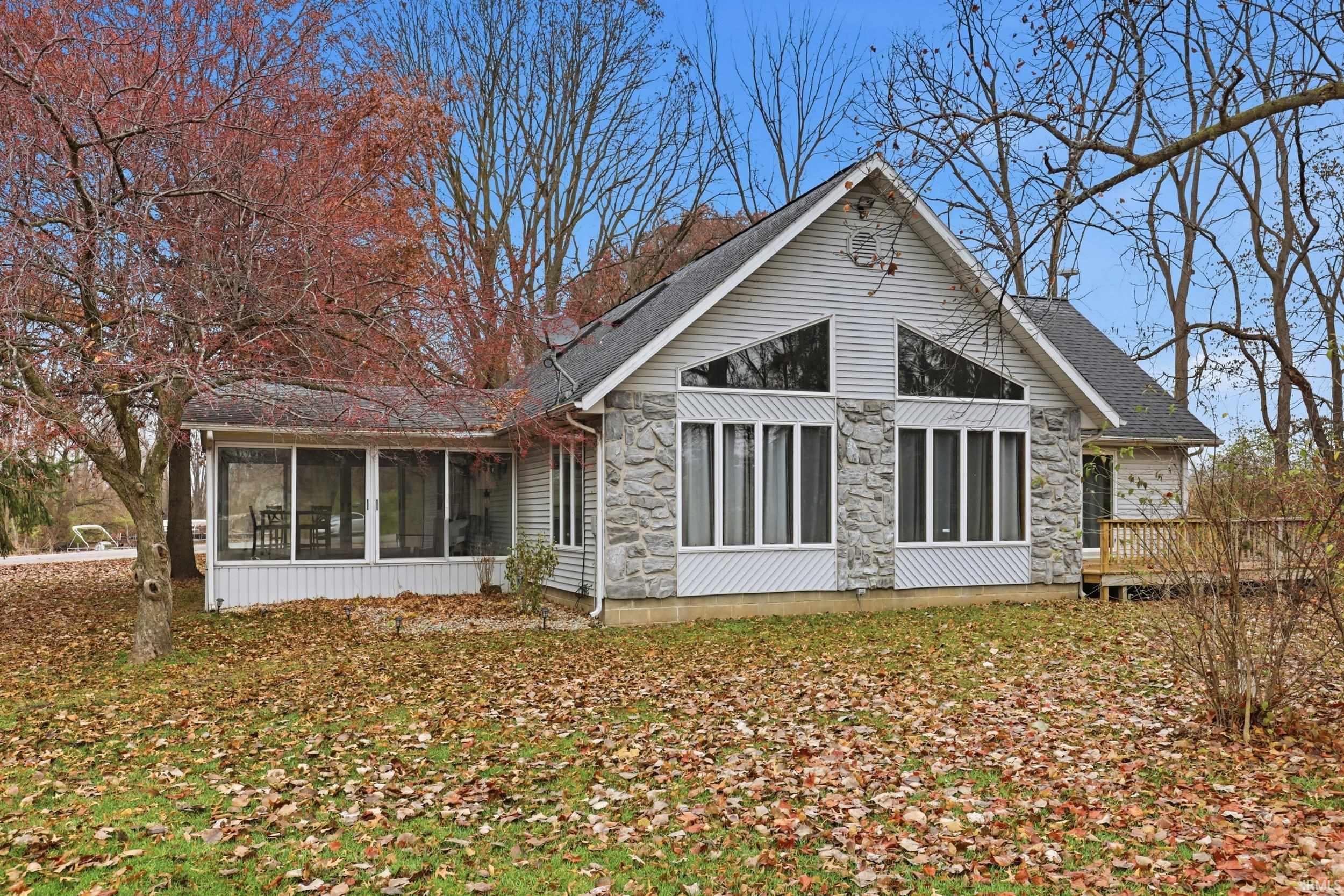 Image 0: Rear view of house with a sunroom, stone siding, and roof with shingles, Back Of Structure Image 0: Rear view of house with a sunroom, stone siding, and roof with shingles, Back Of Structure