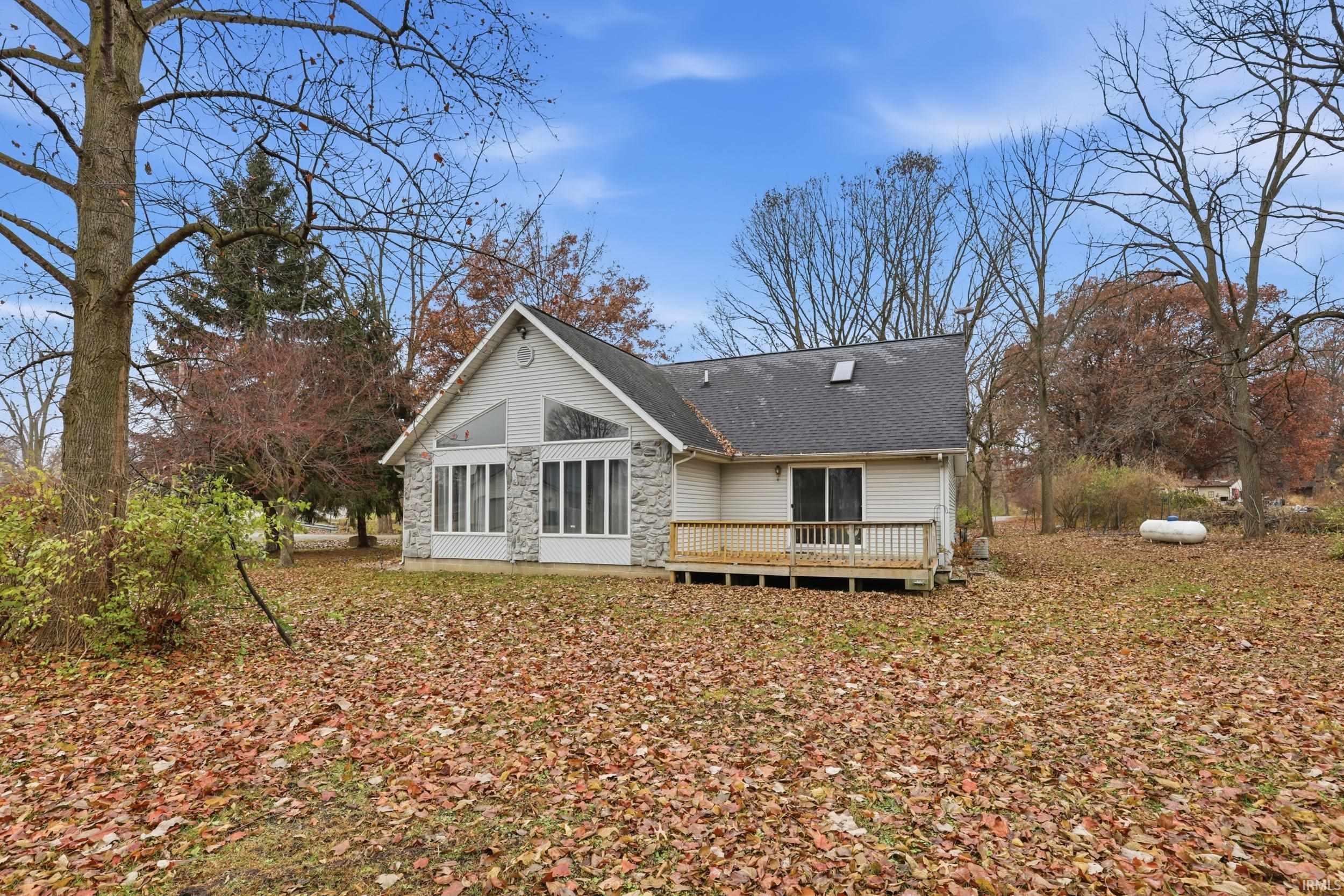Image 1: Back of house with a deck, a shingled roof, and stone siding, Back Of Structure Image 1: Back of house with a deck, a shingled roof, and stone siding, Back Of Structure