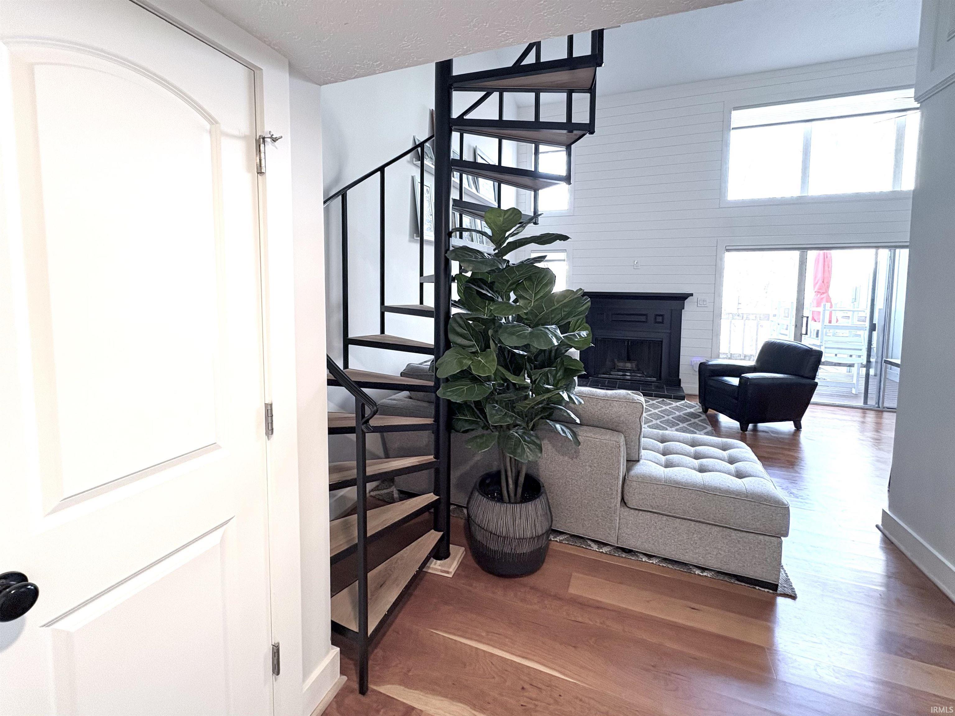 Image 3: Living area with wood finished floors, a fireplace, stairs, and a textured ceiling, Living Room