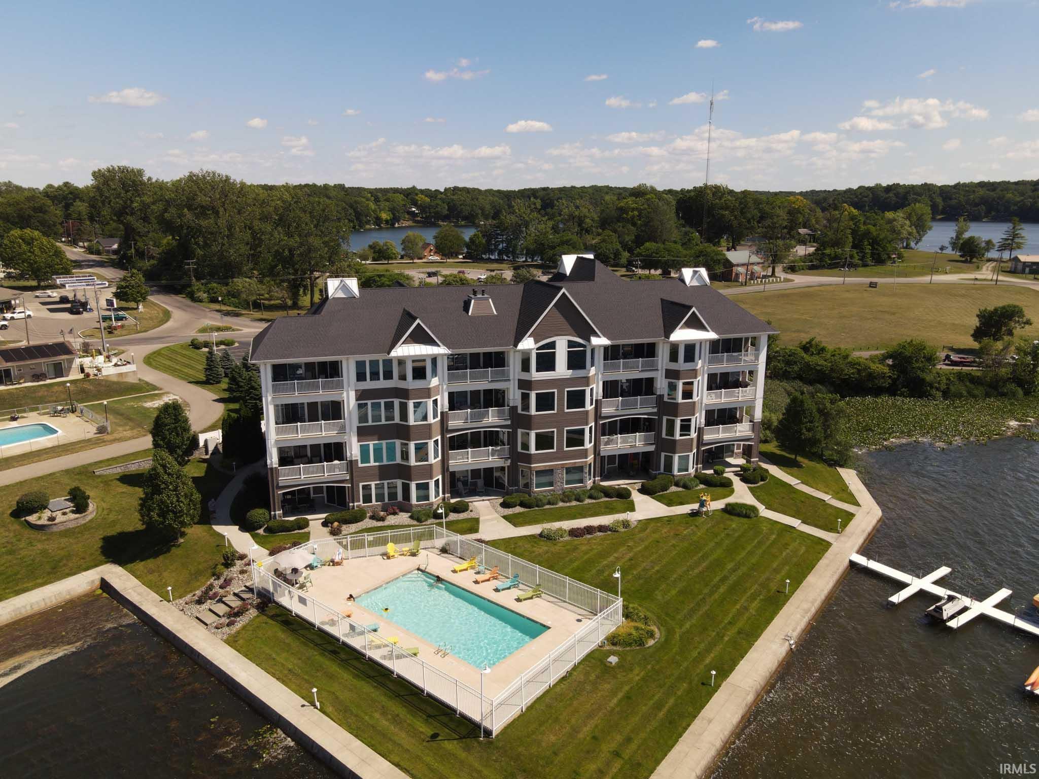 Image 3: Multi-story lakefront building featuring a dark shingle roof and multiple balconies, Aerial View Image 3: Multi-story lakefront building featuring a dark shingle roof and multiple balconies, Aerial View