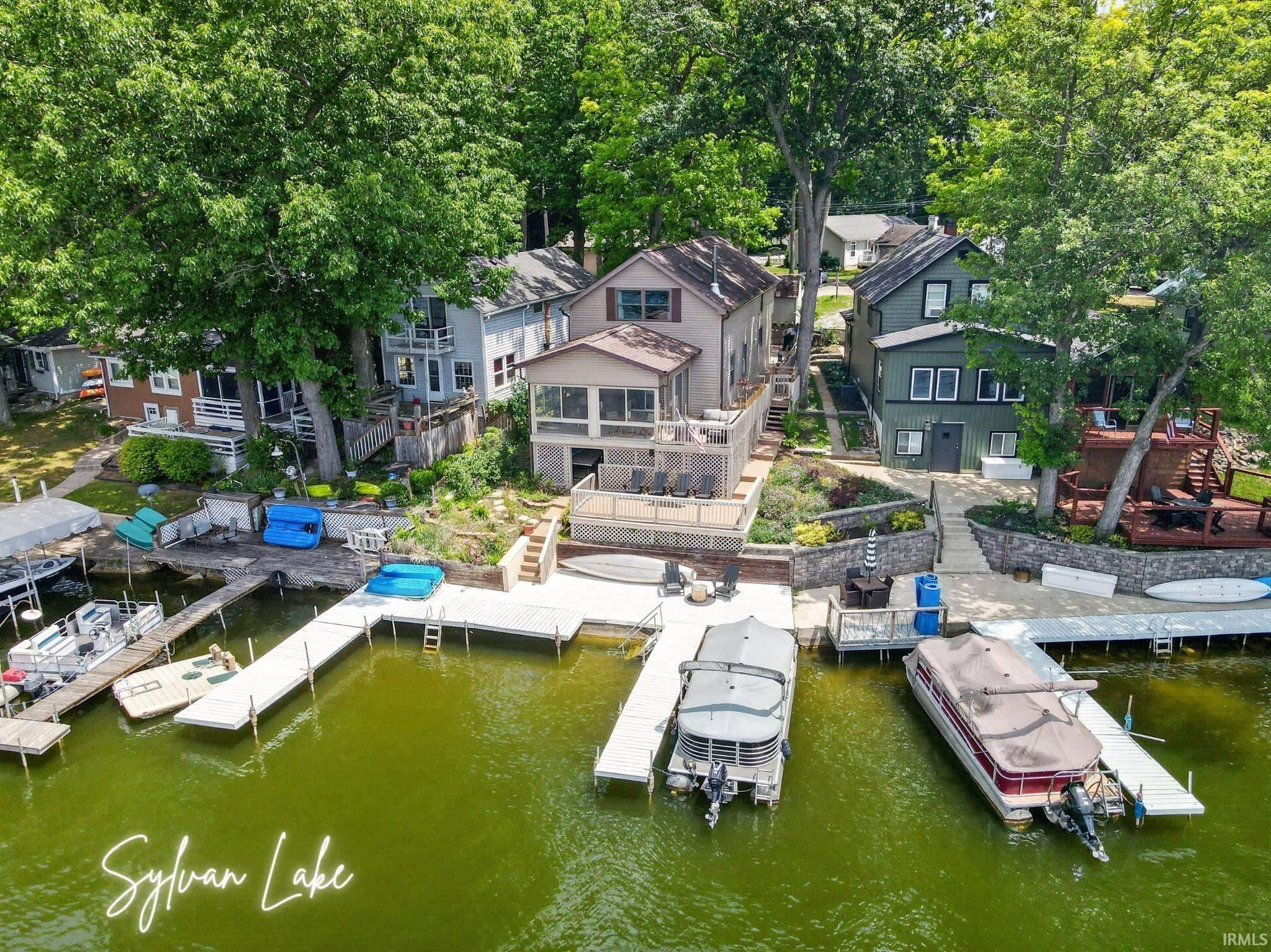 Image 0: Waterfront property featuring a multi-level deck, direct lake access, multiple boat docks, a screened-in porch, and mature trees, Dock