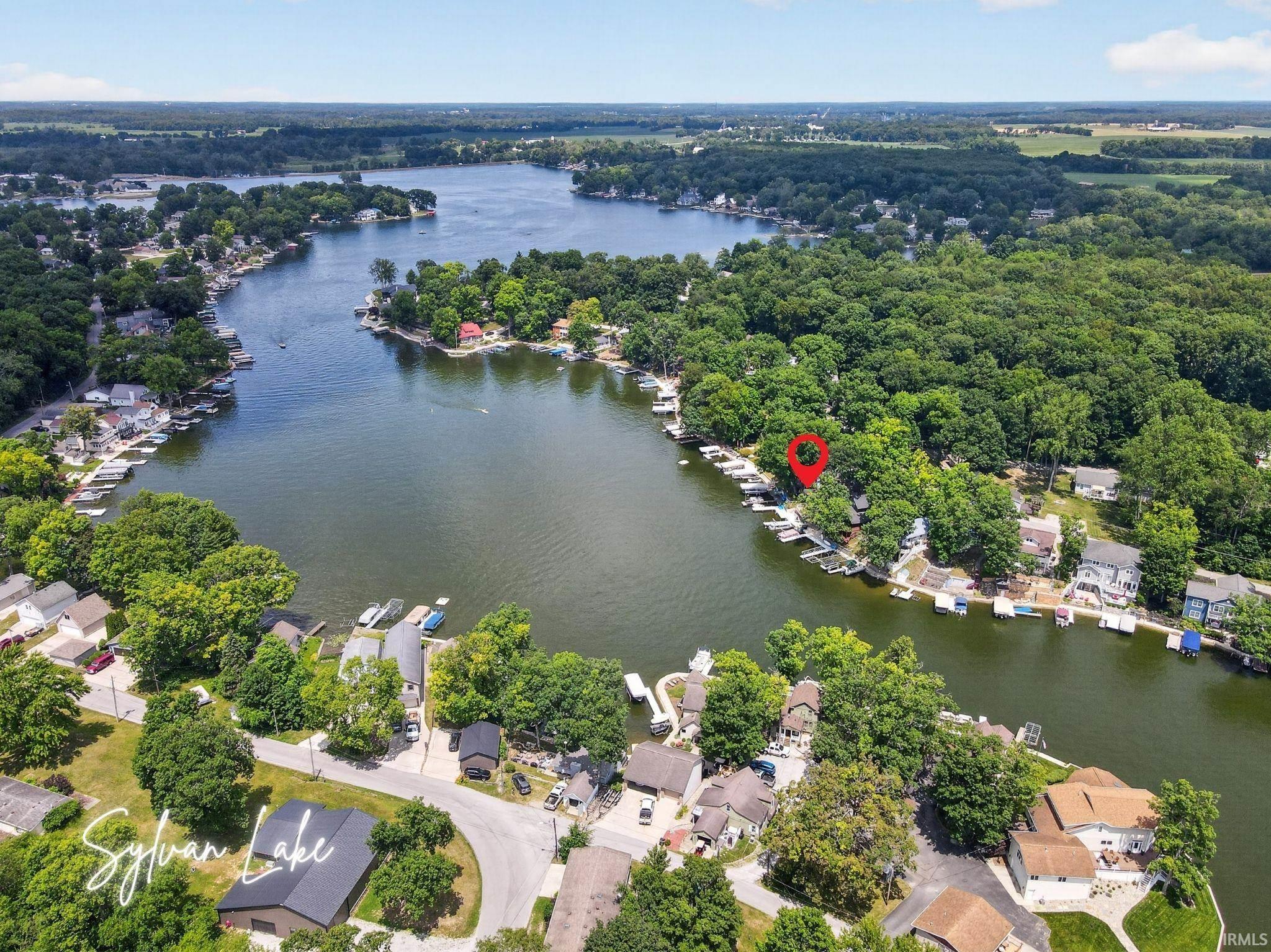 Image 1: Aerial perspective of Sylvan Lake featuring abundant mature trees and surrounding properties, Aerial View