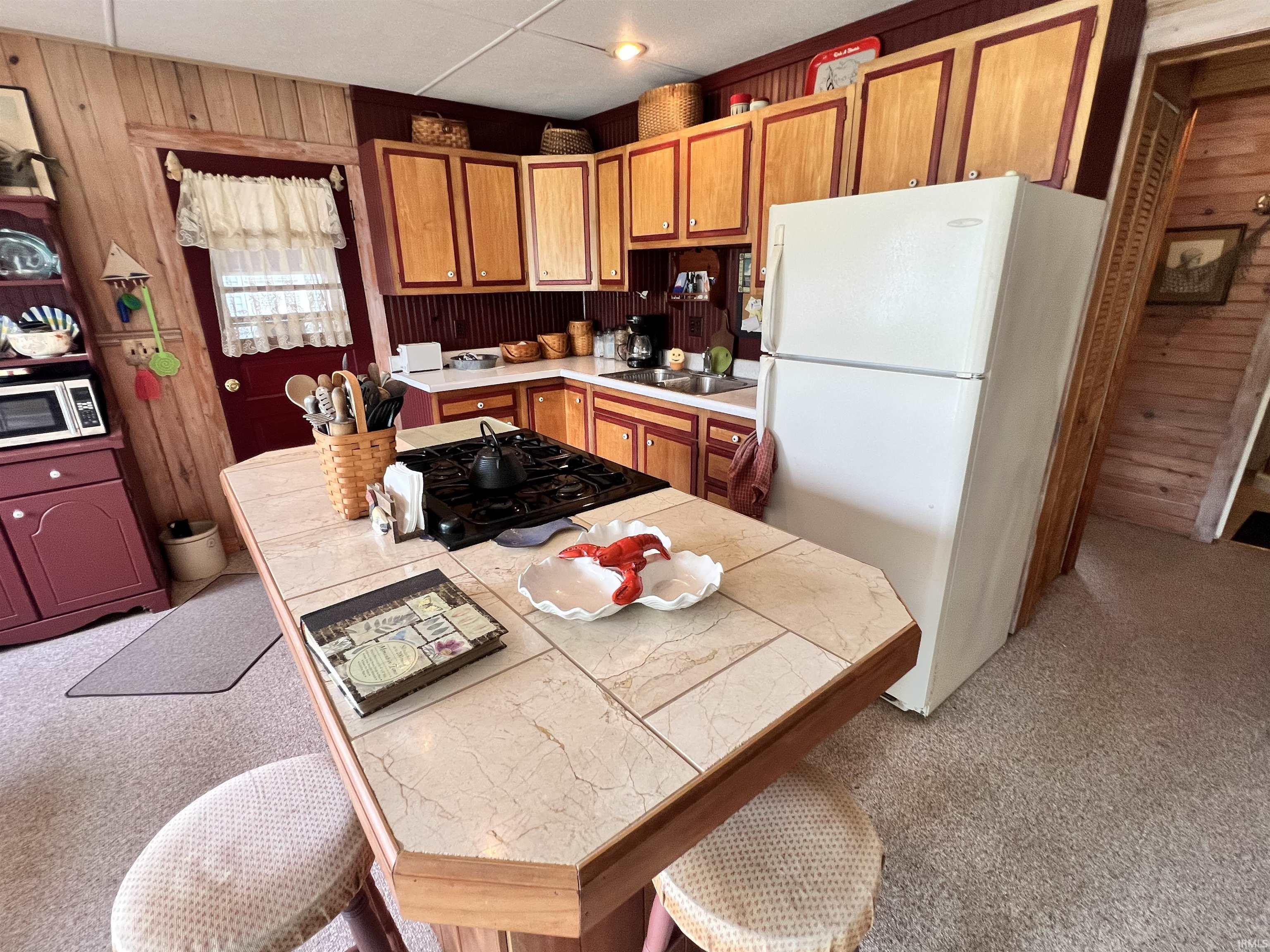 Image 2: Kitchen featuring a central island with a tiled countertop, built-in gas range, and seating, Kitchen