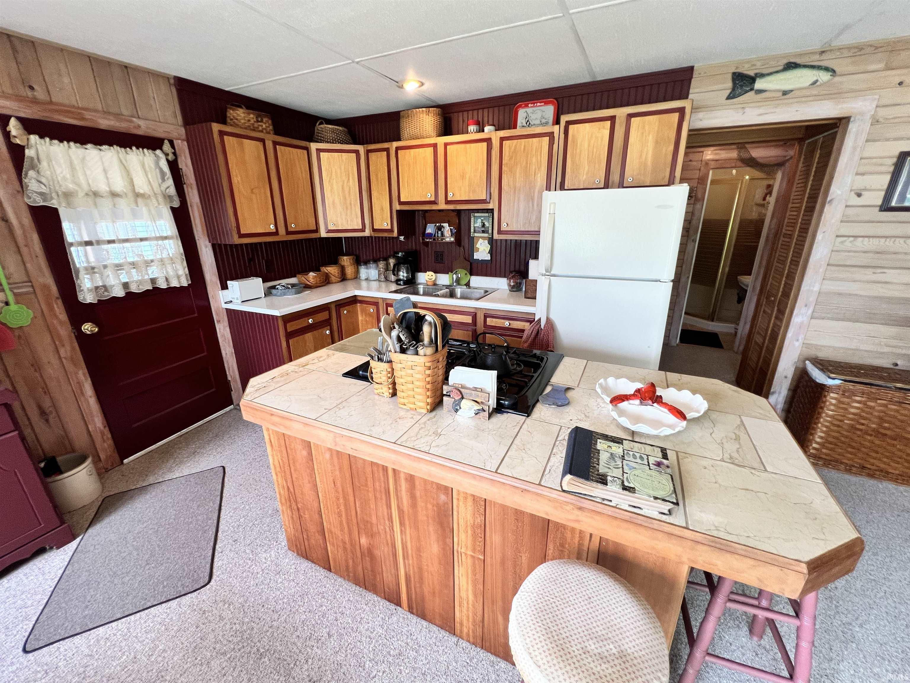 Image 3: Kitchen featuring wood-paneled island with tile countertop, wood cabinetry, and white appliances, Kitchen